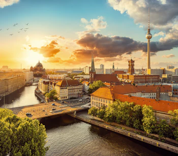 Gyldent aftenlys over Berlins skyline med TV-tårnet ved Alexanderplatz og den historiske Berlin Domkirke ved Spreefloden