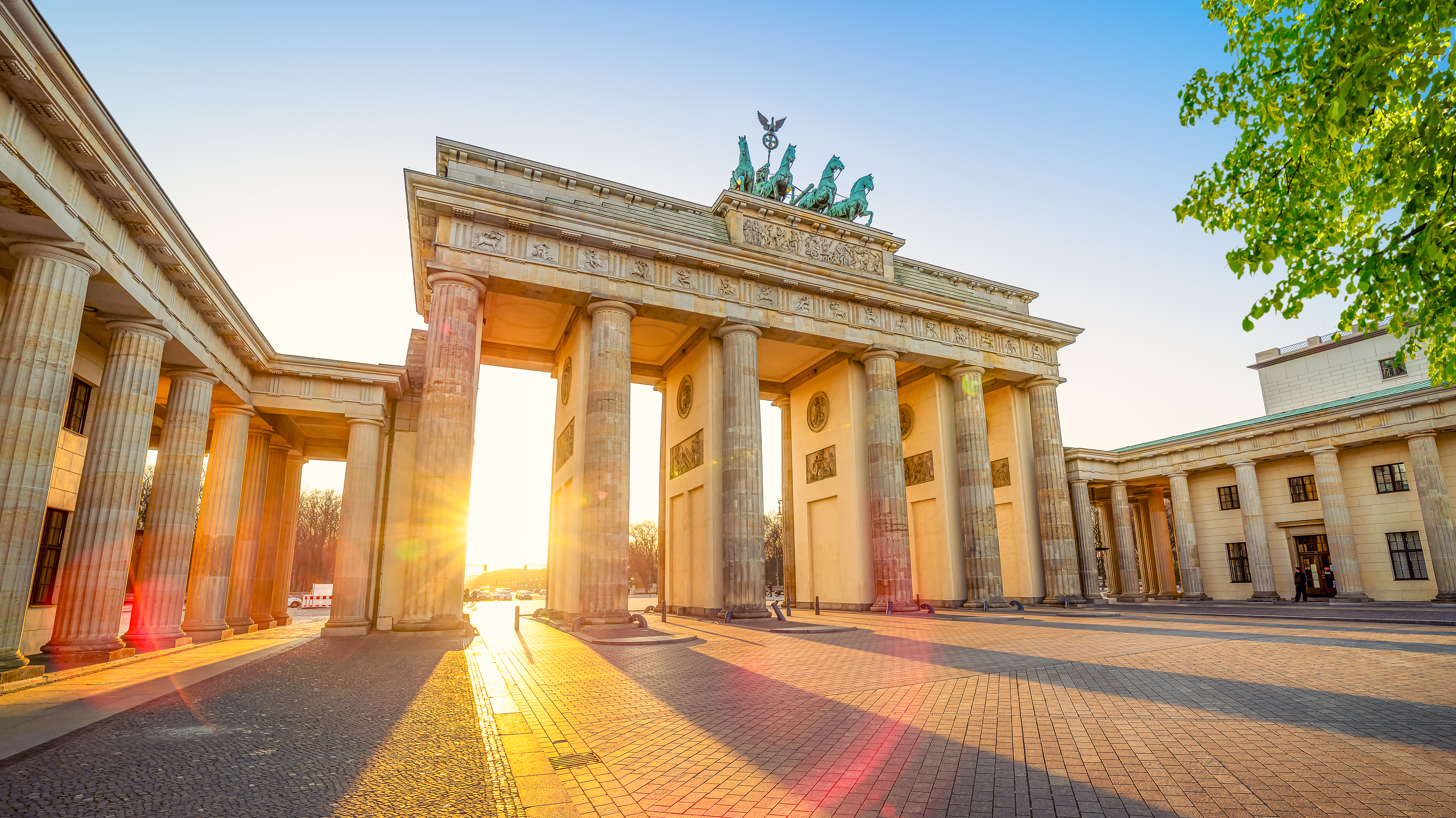 Betagende udsigt til Brandenburger Tor i solnedgangslys, hvor Berlins mest kendte vartegn med den ikoniske Quadriga-statue på toppen fremstår majestætisk i aftensolen