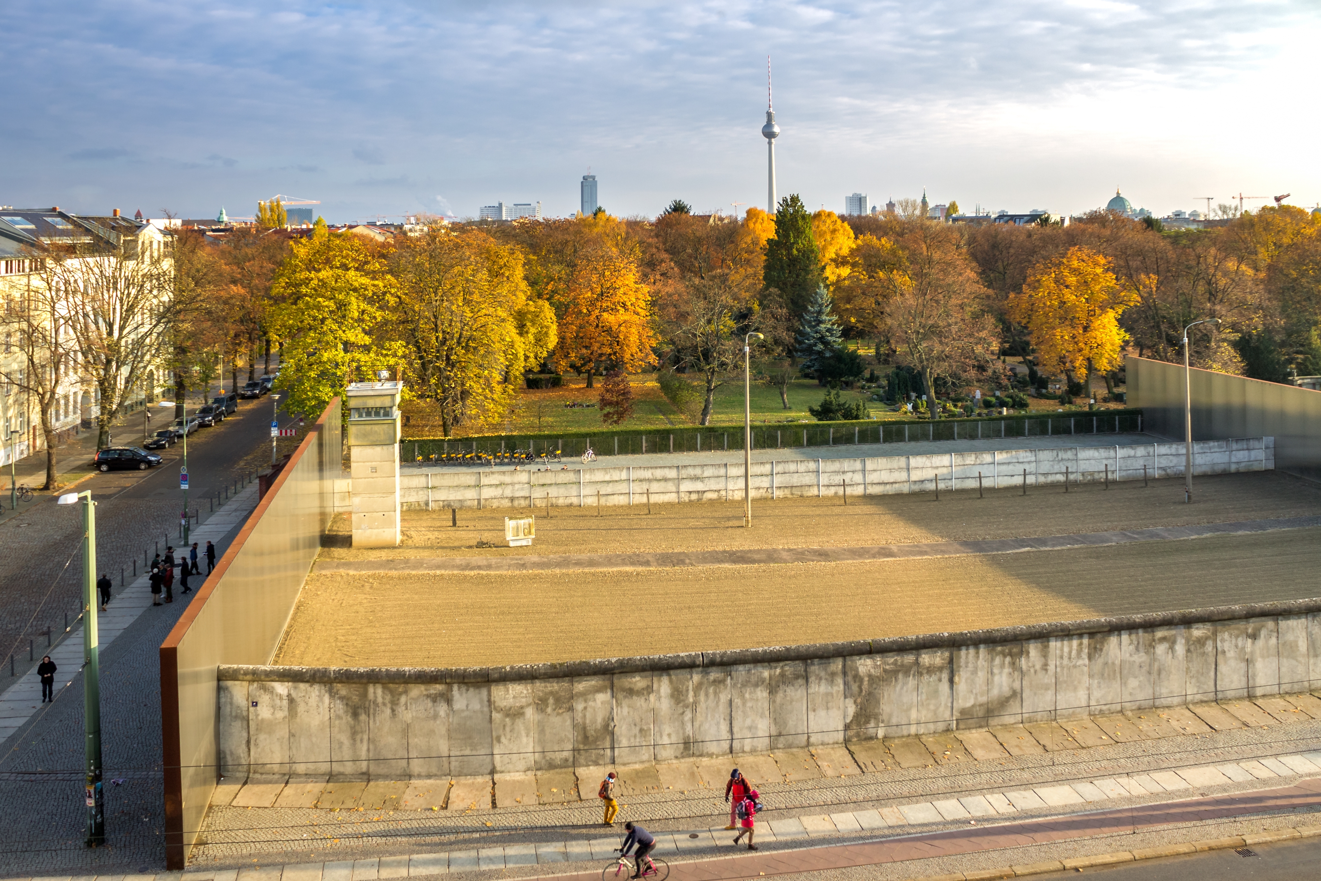 Det historiske Berlinmur-mindested på Bernauer Strasse fotograferet fra oven med gylden efteraarsfarver og Berlins TV-tårn i baggrunden