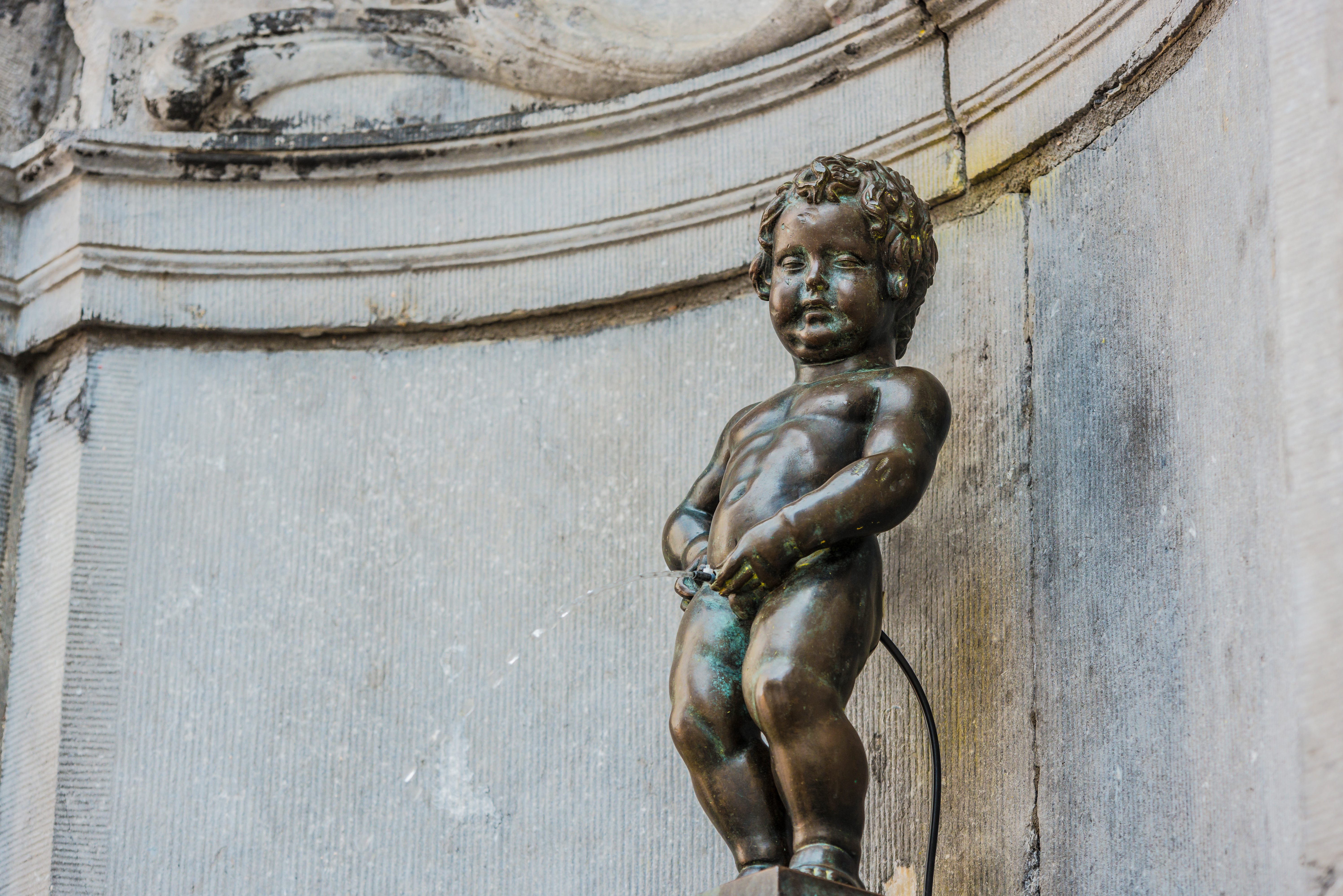 Den berømte Manneken Pis statue i Bruxelles, Belgien - historisk bronzeskulptur og populær turistattraktion i byens hjerte
