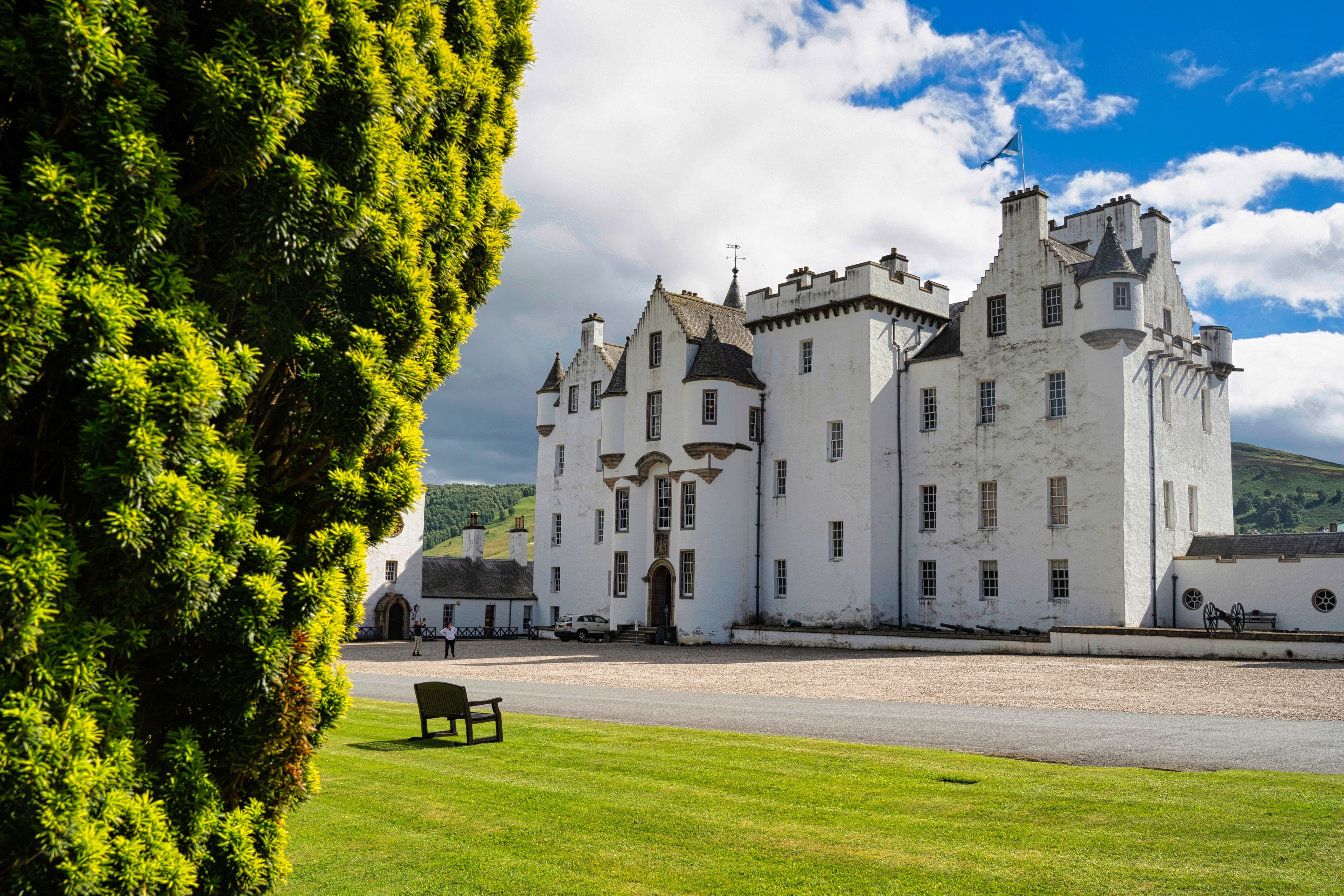 Rejse til Blair Atholl slot i Skotland, indrammet af natur og sommergrønne træer.