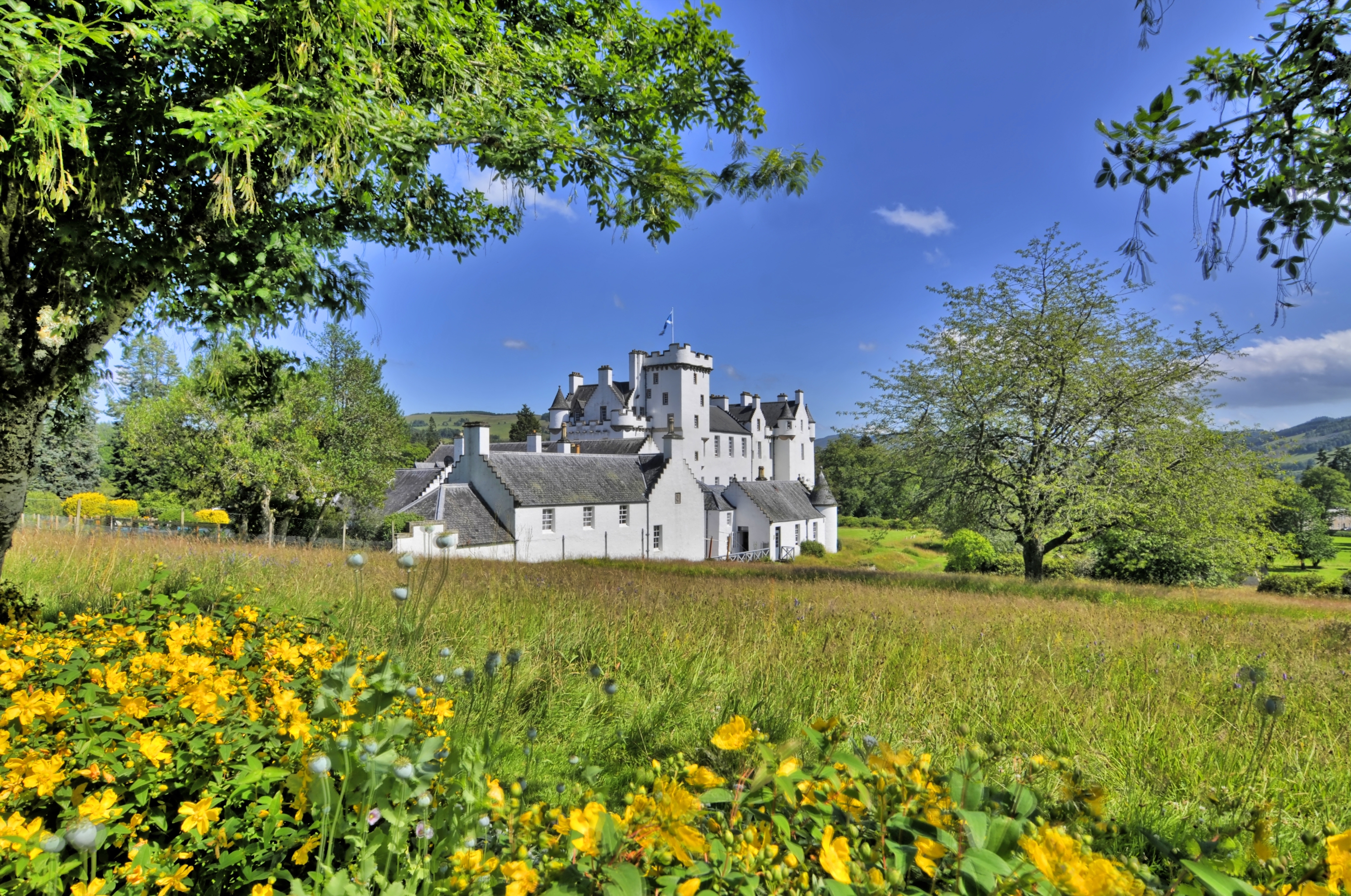 Blair Castle ved Blair Atholl i det smukke skotske højland i Perthshire med gule blomster og grønne marker foran det hvide slot