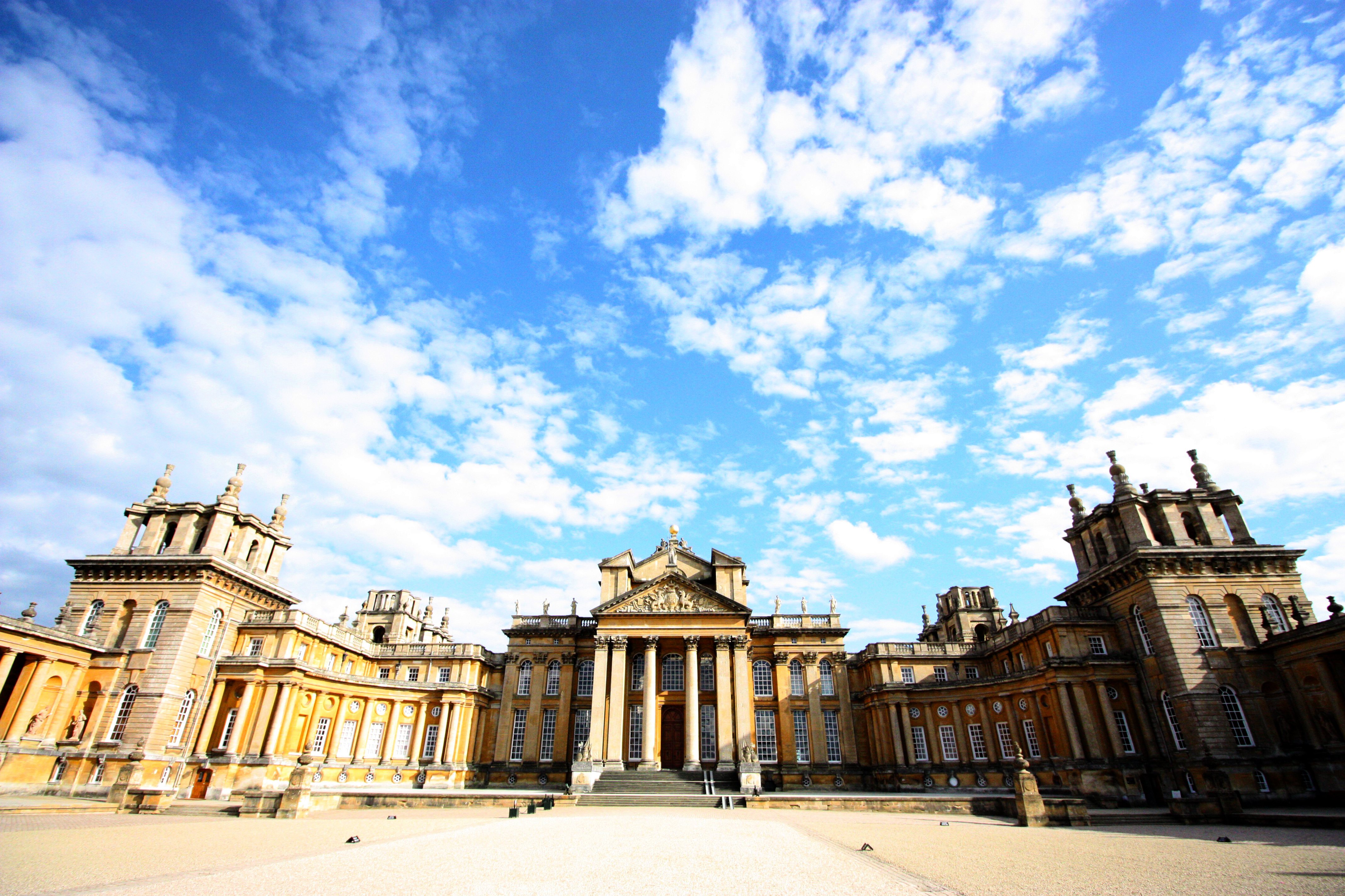 Blenheim Palace prangende barokslot med symmetriske fløje og ornamenterede tårne under dramatisk engelsk himmel