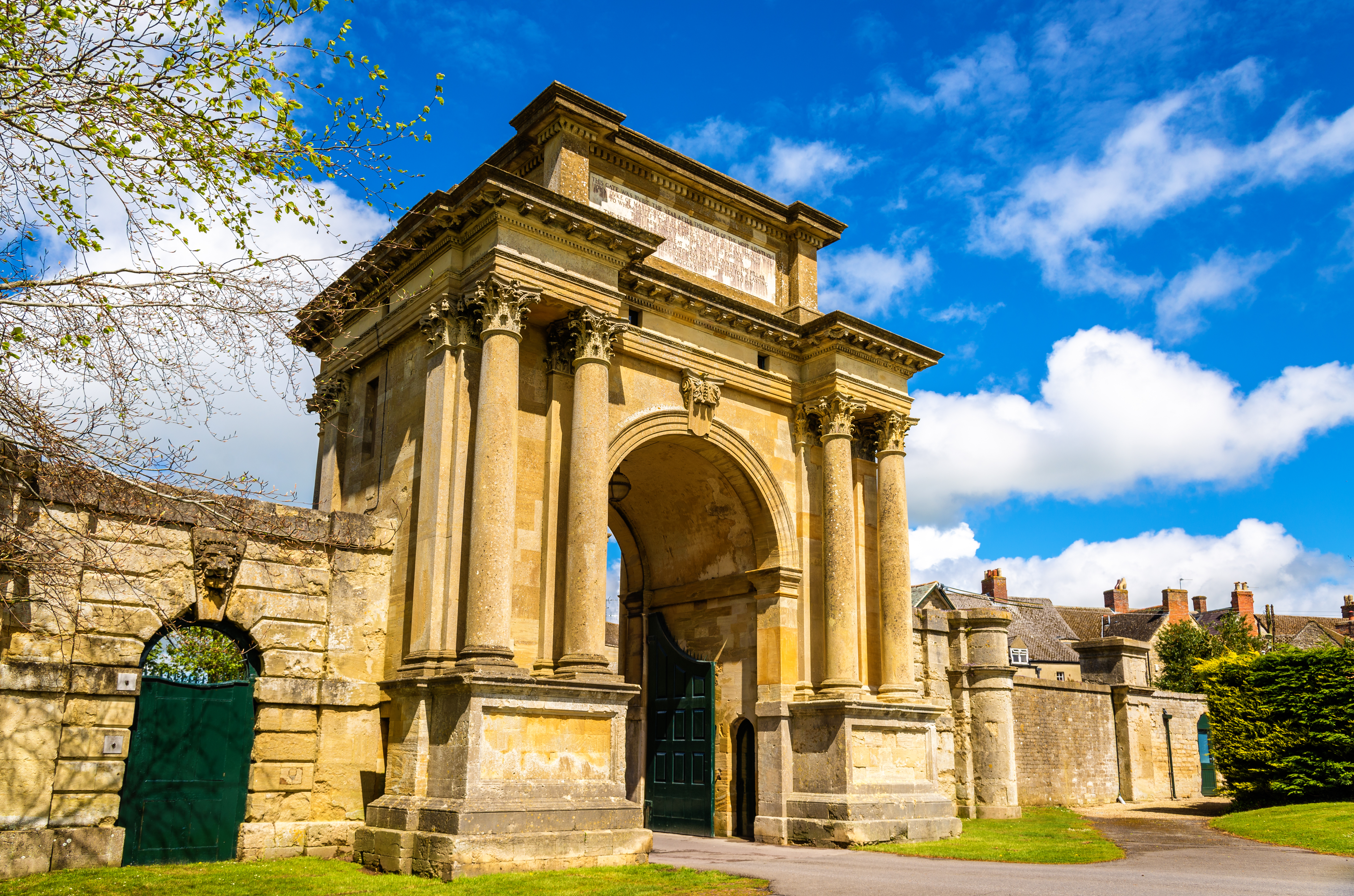 Smukt bevaret barokport ved Blenheim Palace i Oxfordshire, England, med karakteristiske korinthiske søjler og en hvælvet stenbue mod en blå himmel