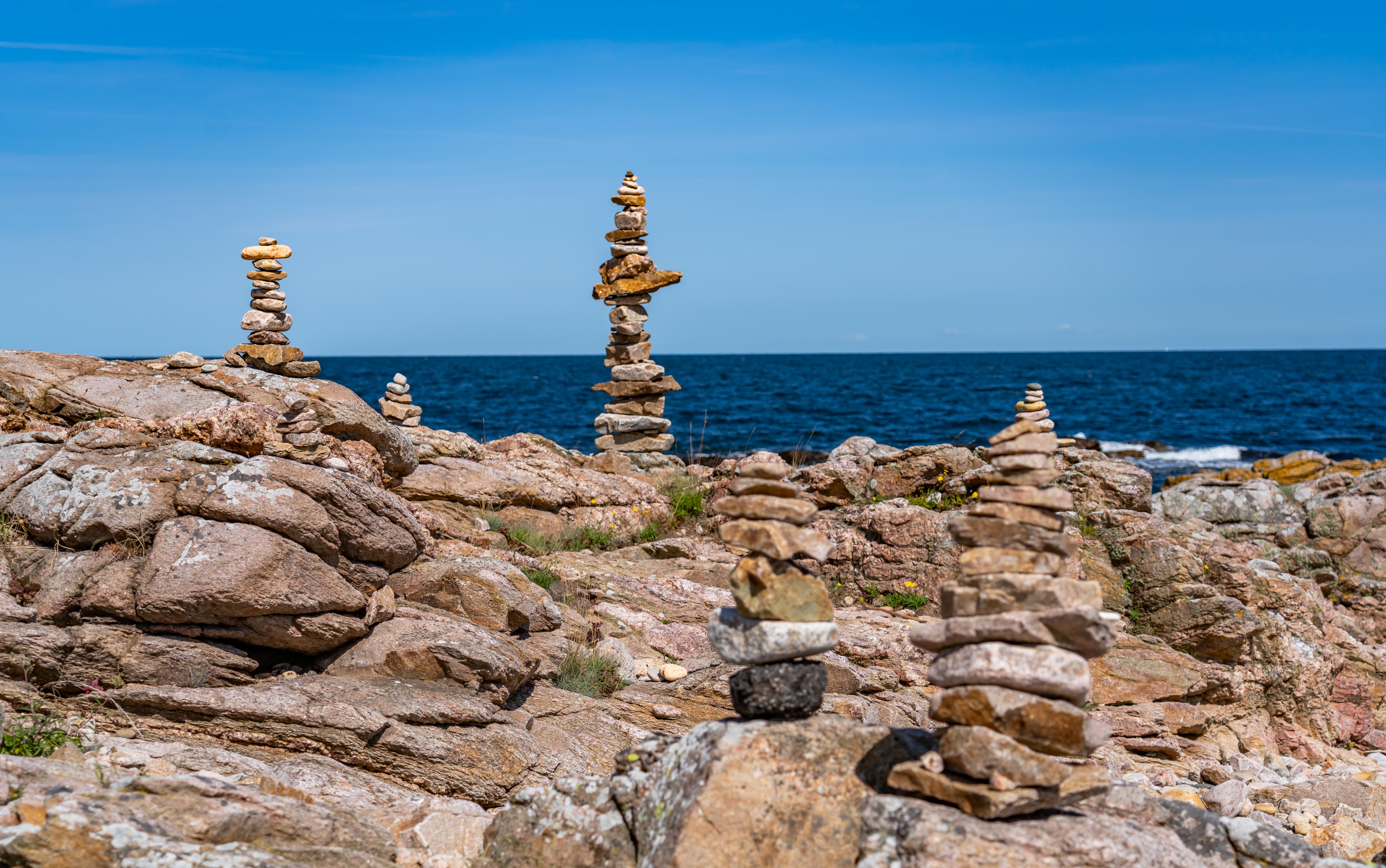 Meditativt stemningsbillede af balancerede stenstakke på klippekysten i Gudhjem på Bornholm