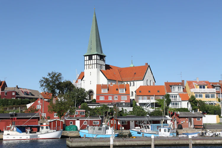 Stemningsfuld havn i Rønne på Bornholm med blå fiskerbåde og den ikoniske hvide kirke i baggrunden