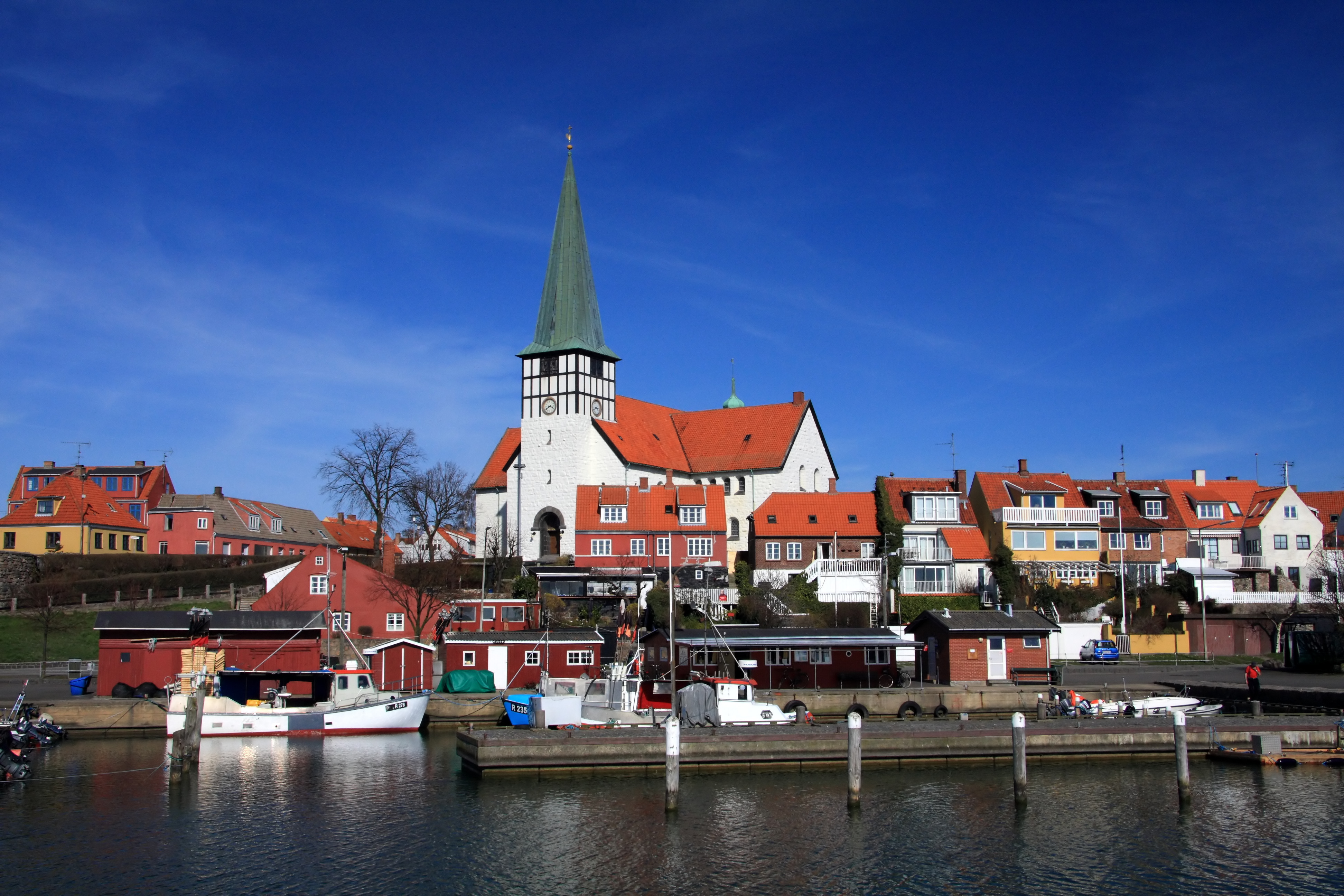 Rønne havnefront med hvide fiskerbåde og den smukke kirke bag røde huse på Bornholm, Danmark