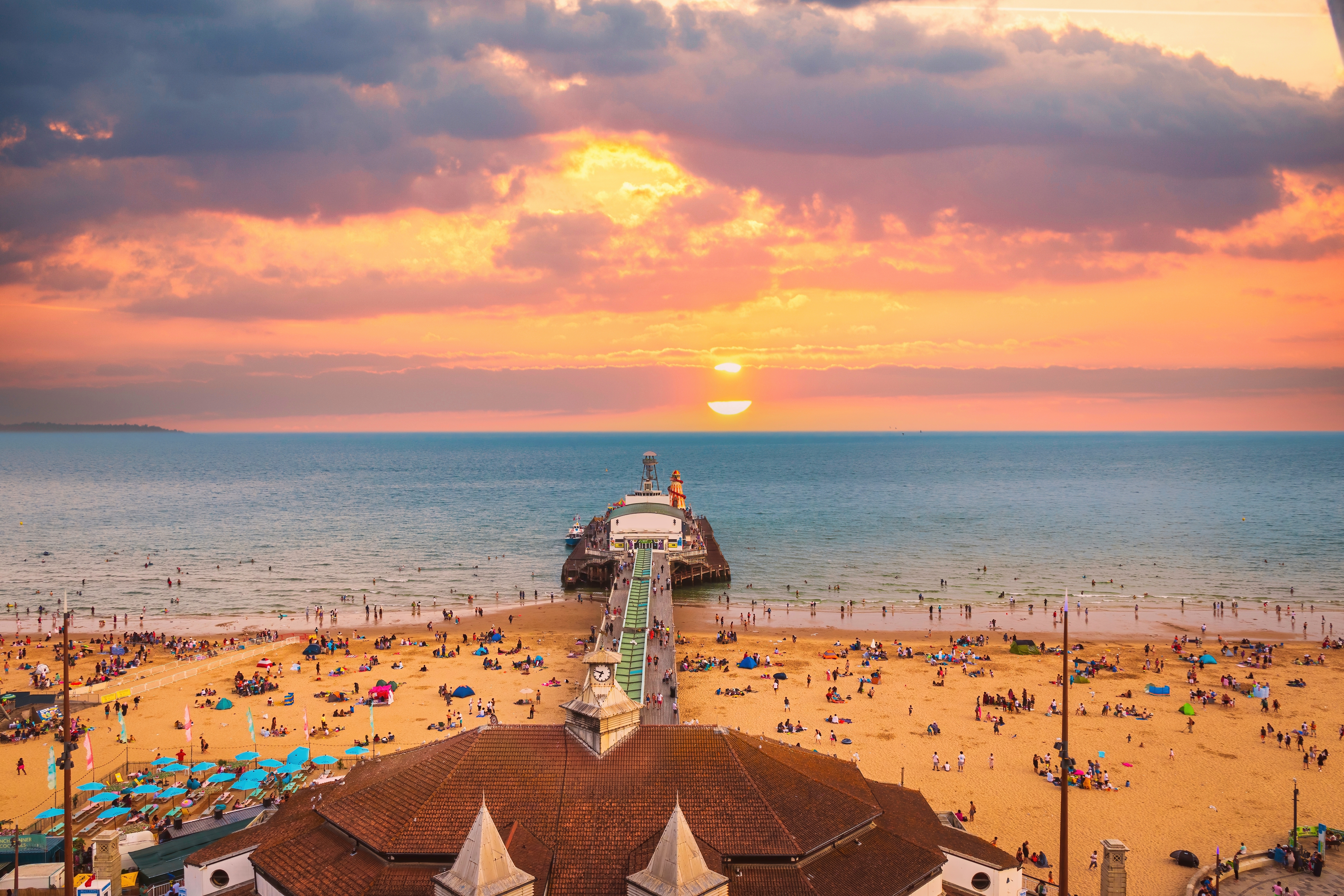 Udsigt over Bournemouth pier og den populære sandstrand ved solnedgang i Dorset, England, med mange feriegæster