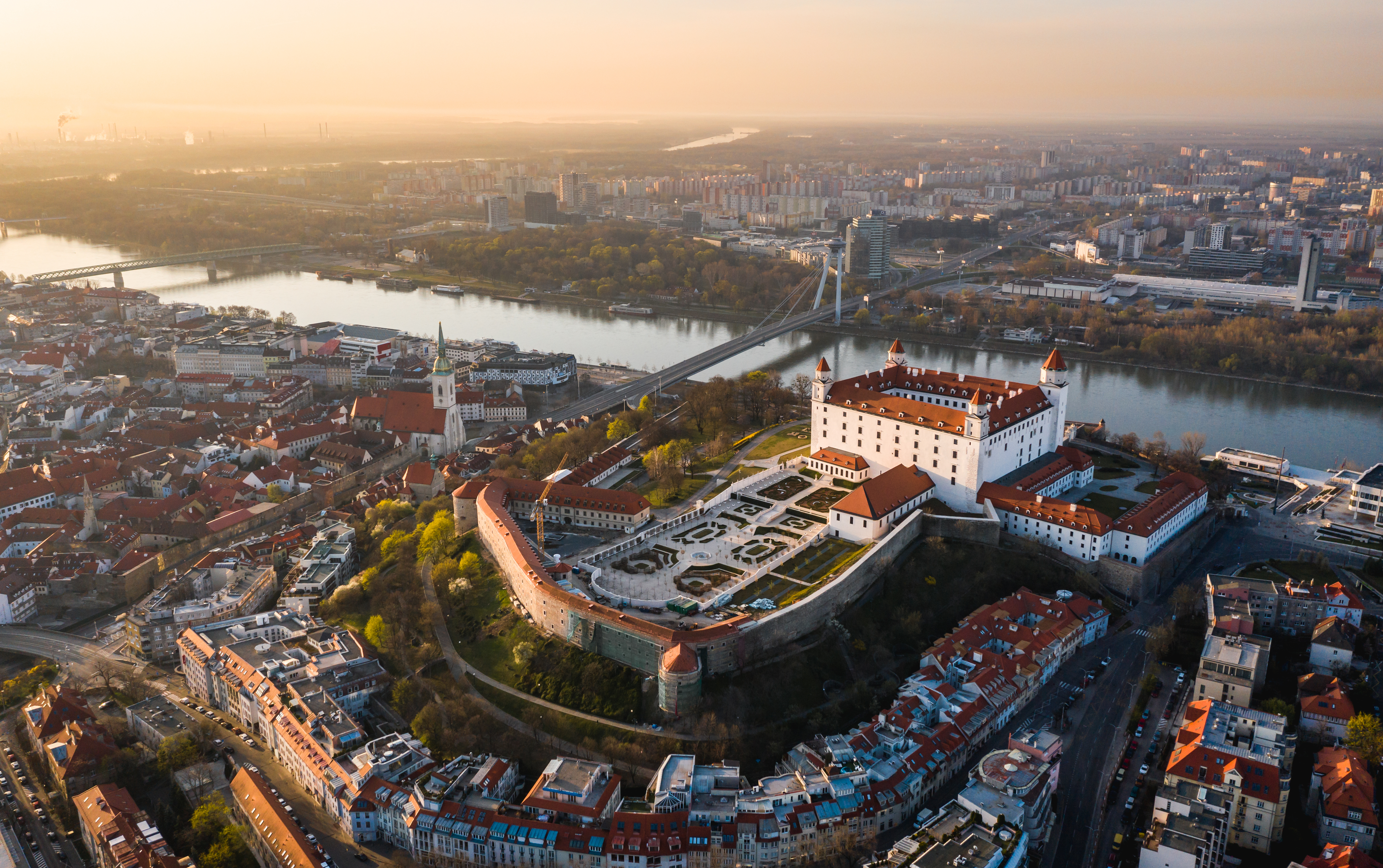 Luftoptagelse af middelalderborg i Bratislava ved Donau-floden med orange solnedgangslys over byen