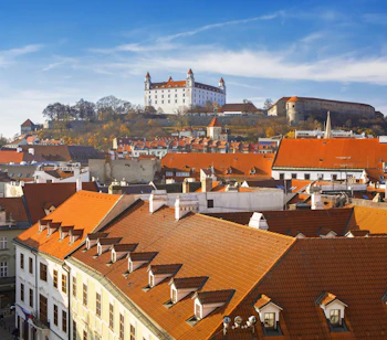 Luftudsigt over Bratislavas gamle bydel med karakteristiske røde tage og det hvide Bratislava Slot på bakken, Slovakiet