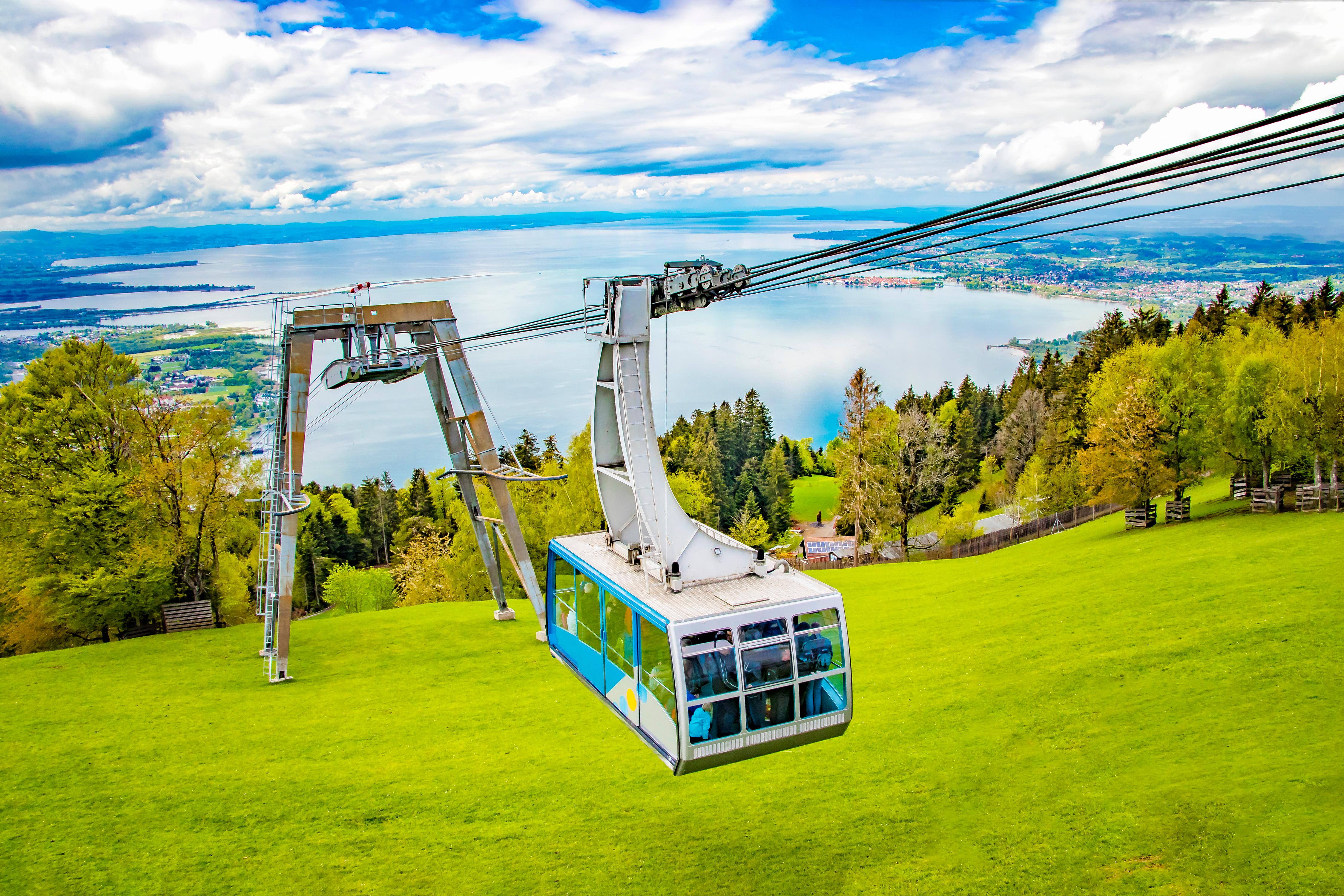 Kabelbane gondol ved Pfänder bjerget med udsigt over den blå Bodensø og Bregenz by omgivet af grønne skove og enge i Østrig