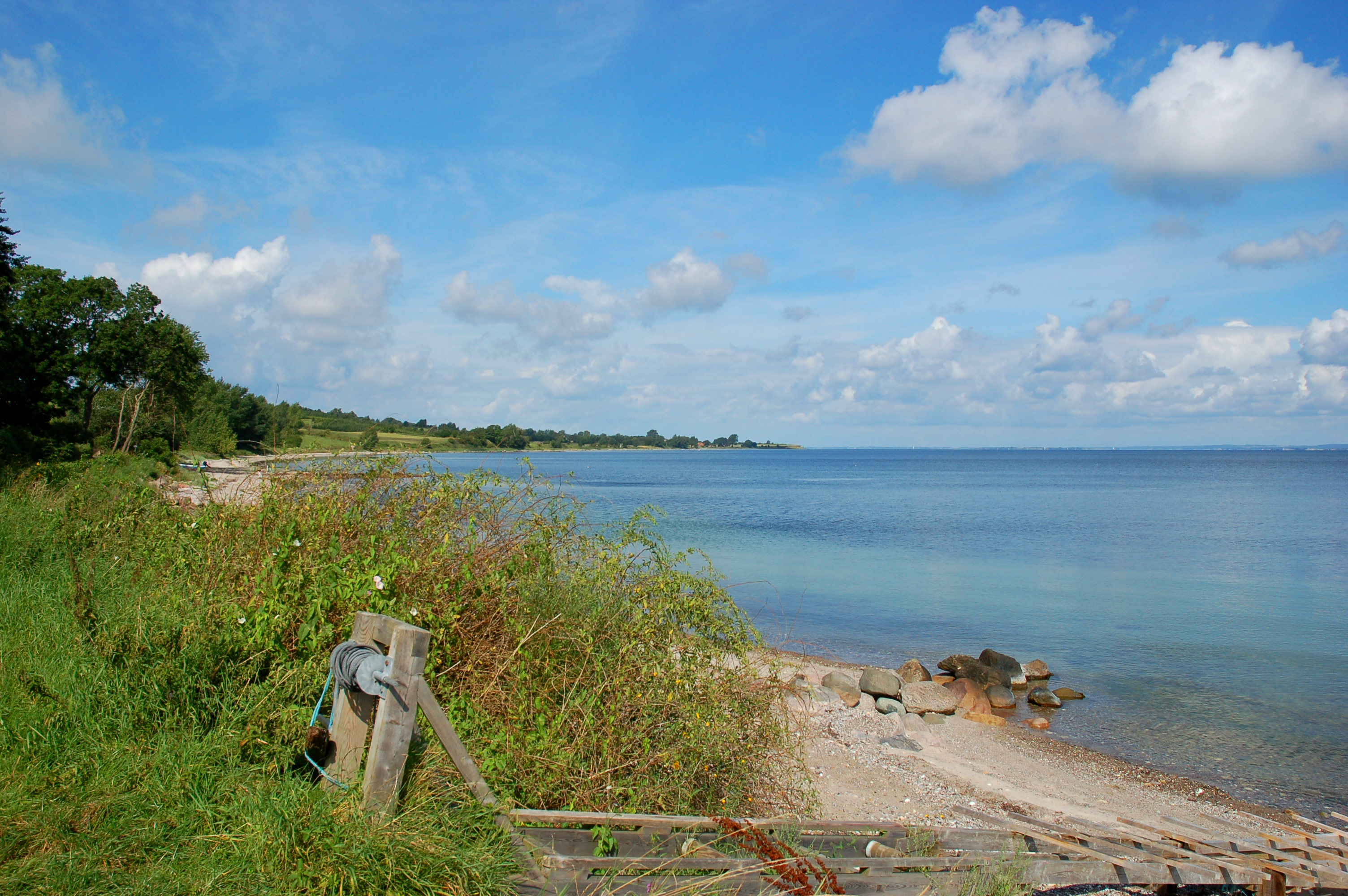Naturskøn dansk strand med stene og krystalklart havvand i sommersolskin