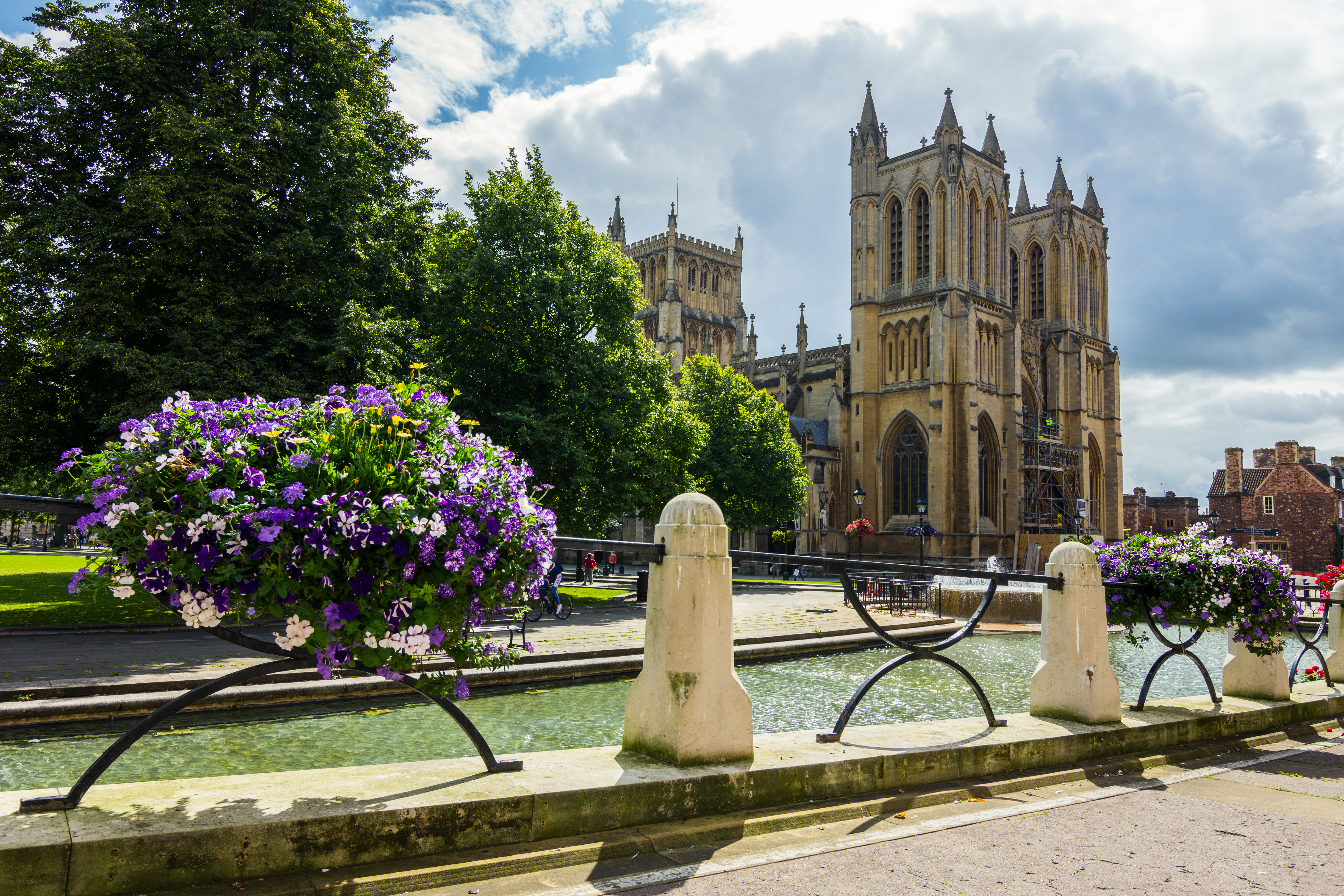 Stemningsfuldt billede af den ikoniske Bristol Katedral med vandspejl fra fontænen og farvestrålende blomsterbede - oplev den charmerende by Bristol på vores kulturrejser til Storbritannien