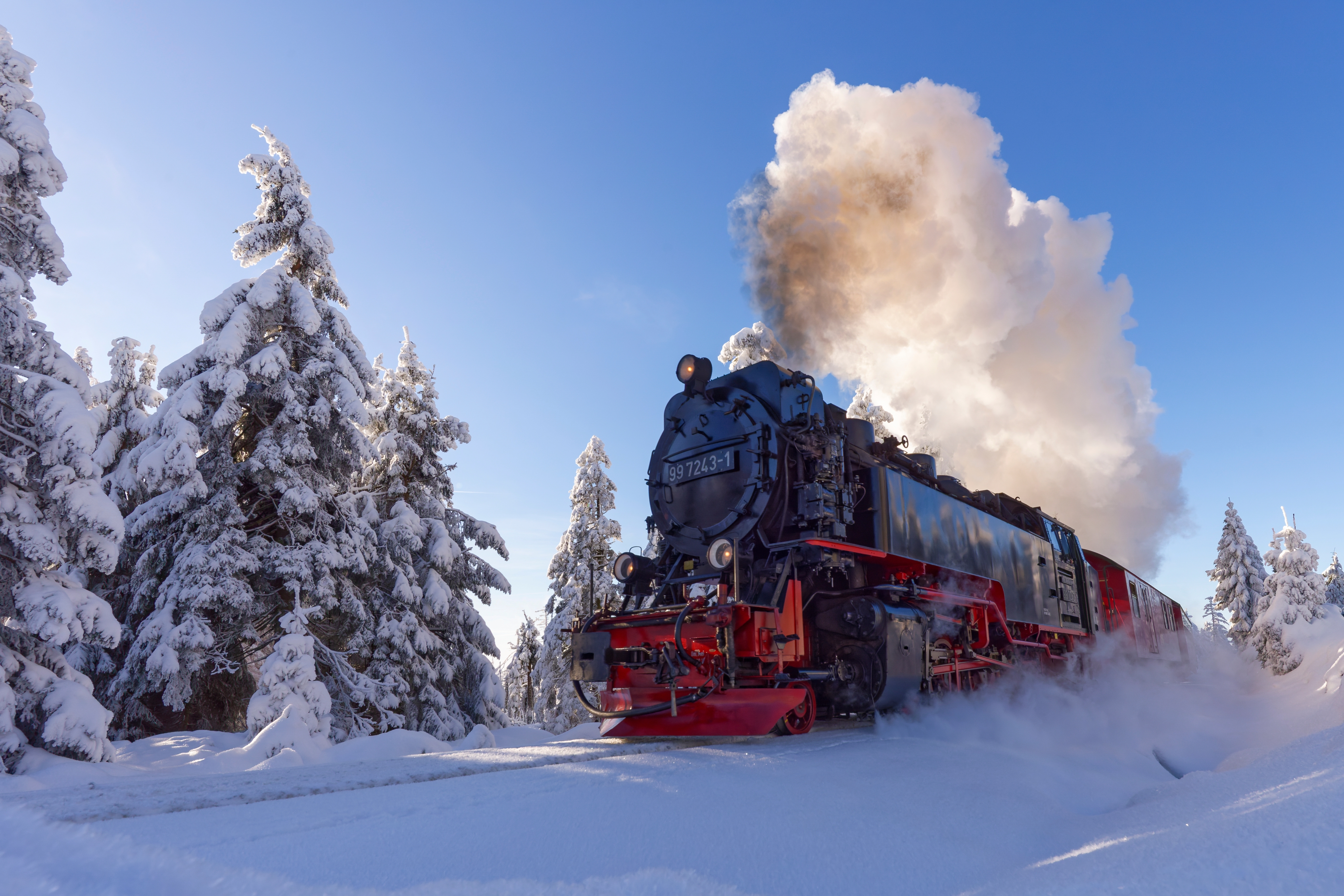 Det ikoniske damplog på Harz smalsporede jernbane omgivet af sneklædte graner på vej mod Brocken i det smukke Harz-bjerglandskab