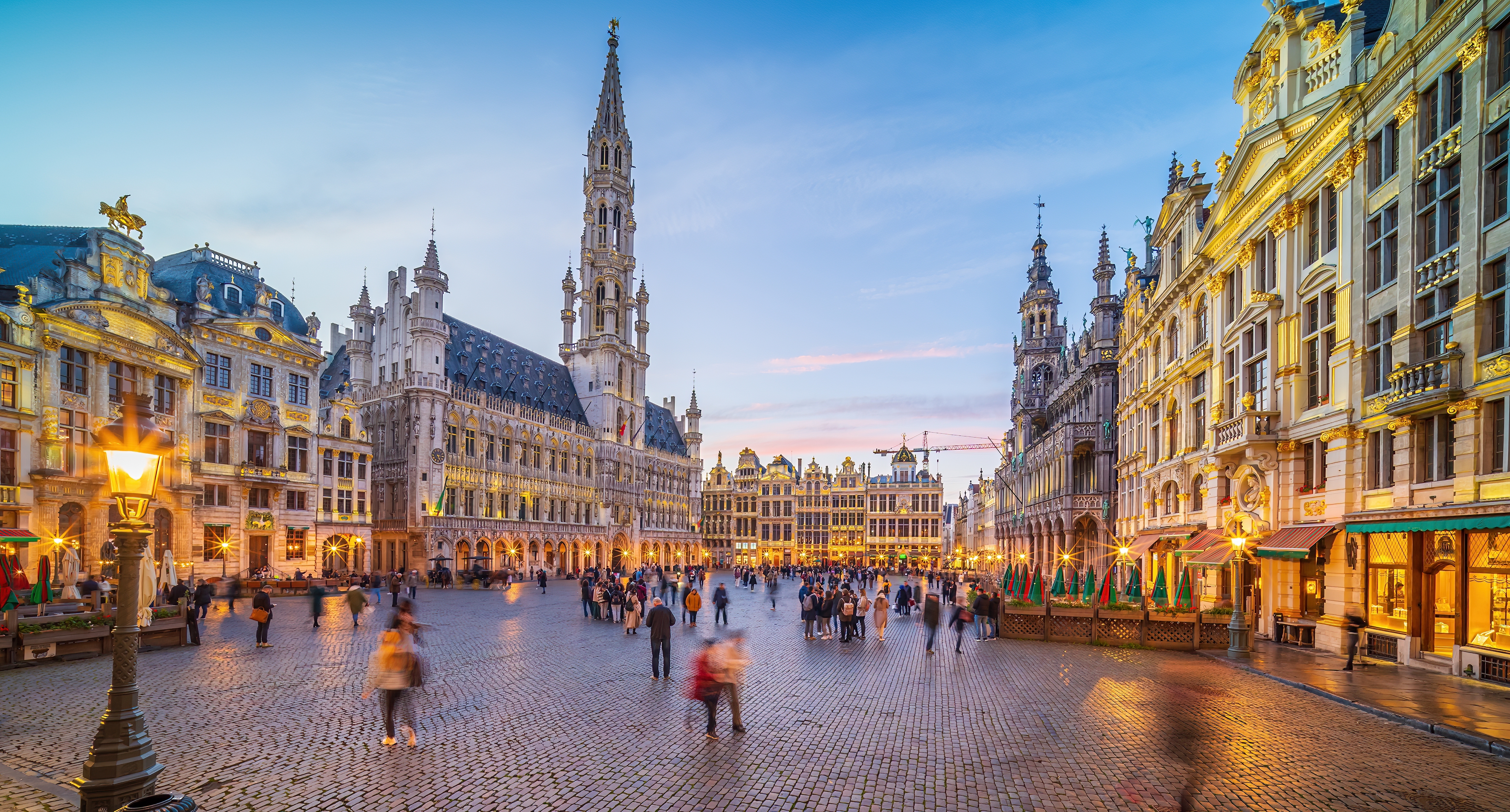 Grand Place i Bryssel med det gotiske rådhus og historiske bygninger der lyser op ved solnedgang i Belgien