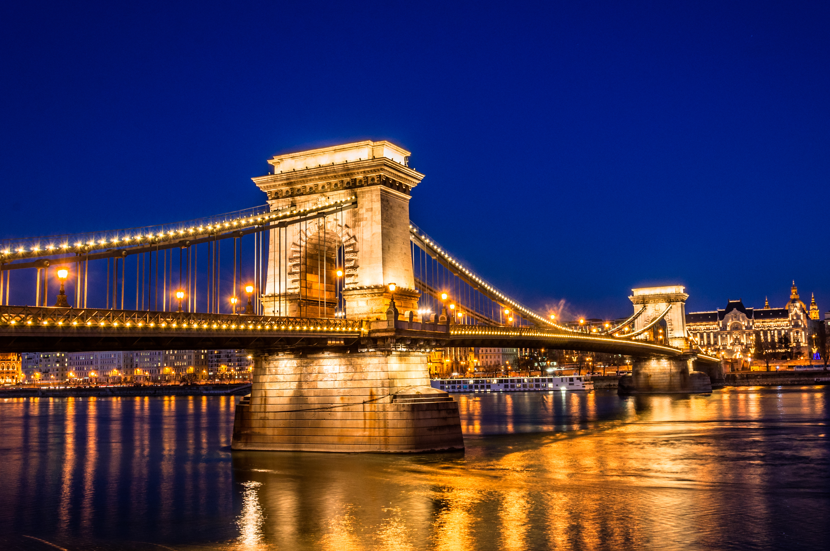 Budapest bybro om aftenen over Donau med gyldne lys og blå himmel