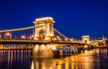 Budapest bybro om aftenen over Donau med gyldne lys og blå himmel