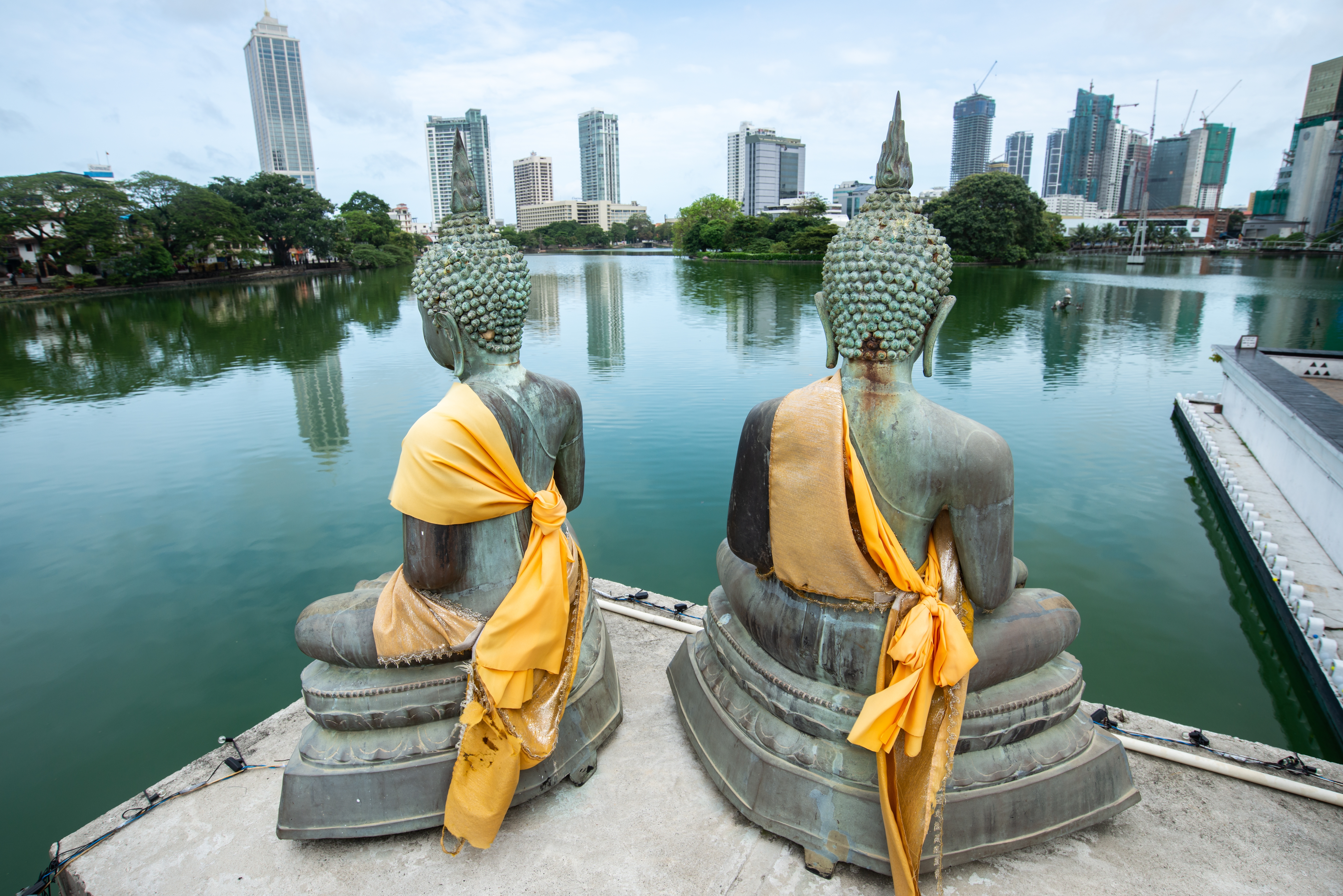 Buddhistiske statuer i orange klæder med panoramaudsigt over Colombo by
