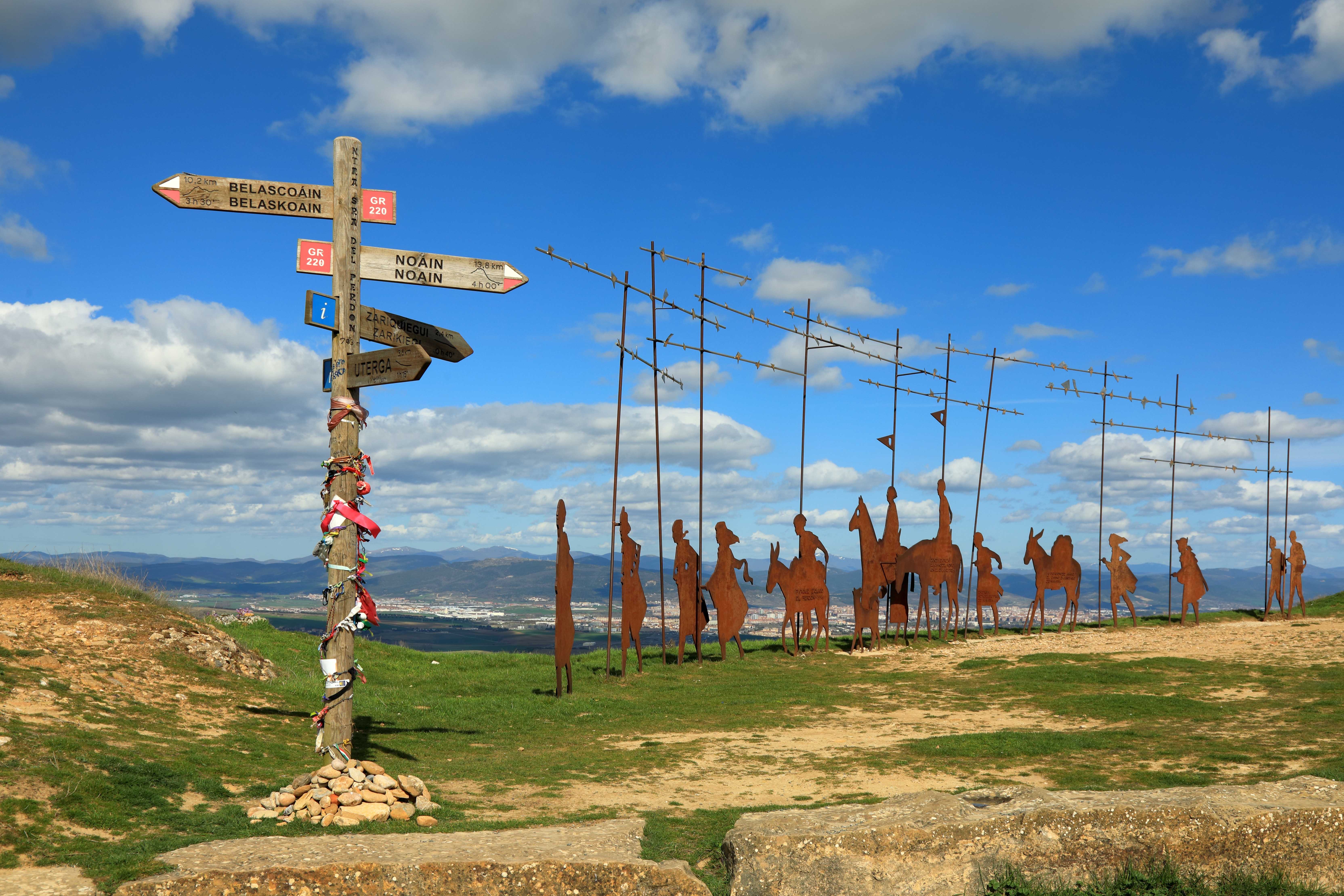 Camino de Santiago med ikoniske pilgrimstatuer og vejskilte under blå himmel