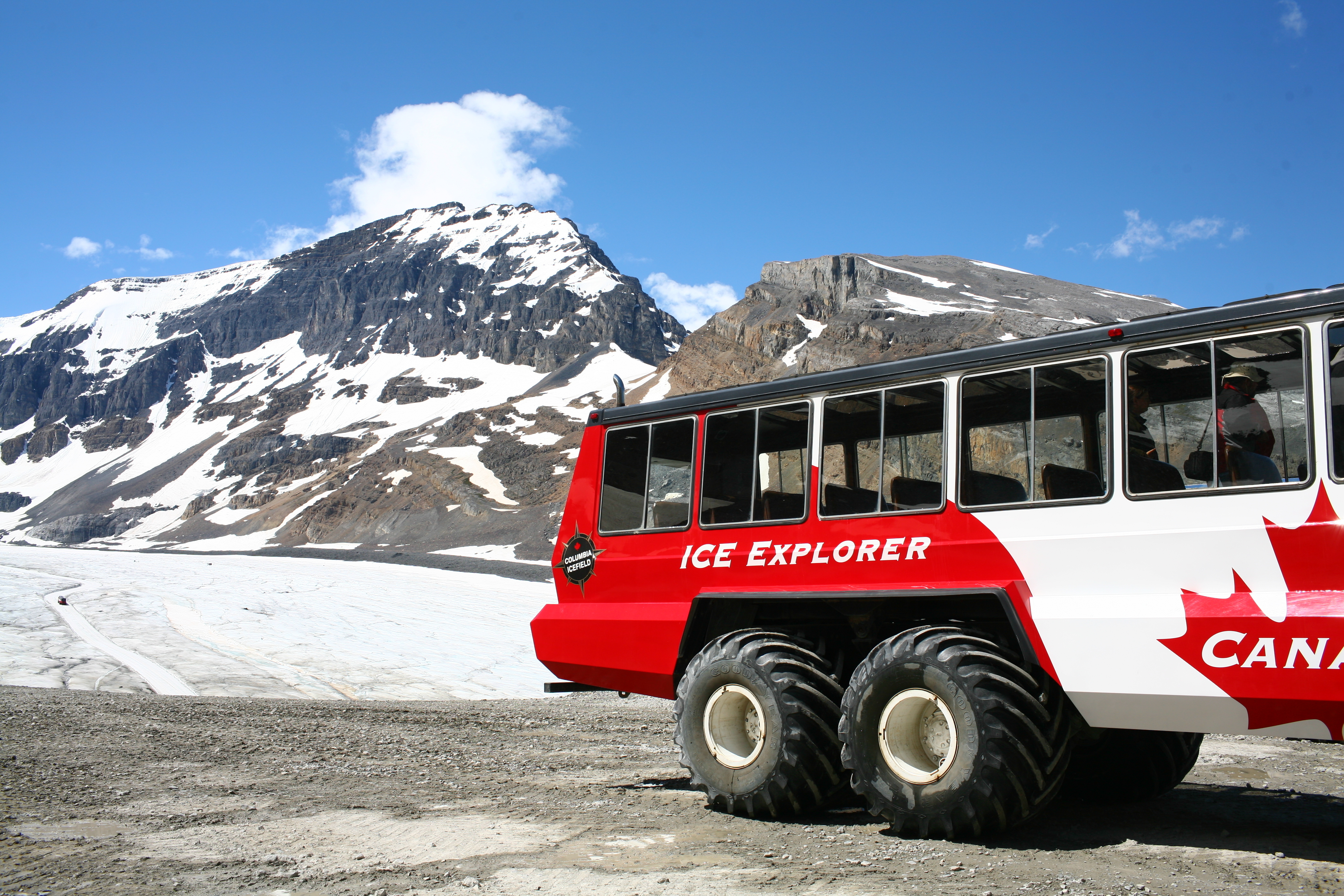 Spektakulær islandskab på Athabasca gletsjeren i Columbia Icefield med rødt ekspeditionskøretøj, omgivet af majestætiske bjerge i Jasper Nationalpark, Canada
