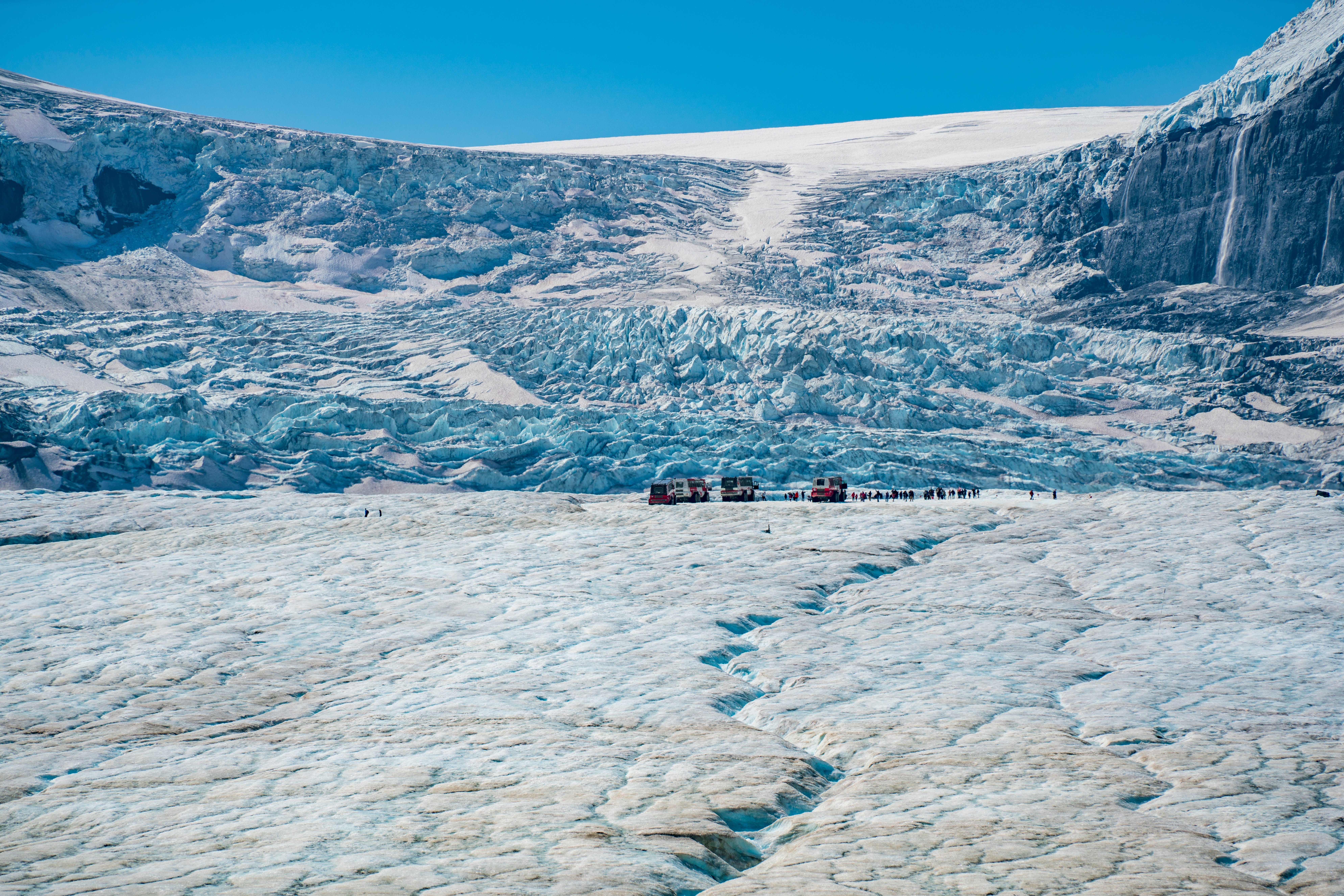 Imponerende gletsjerlandskab med dybe isrevner og turister på Columbia Icefield i de canadiske Rocky Mountains
