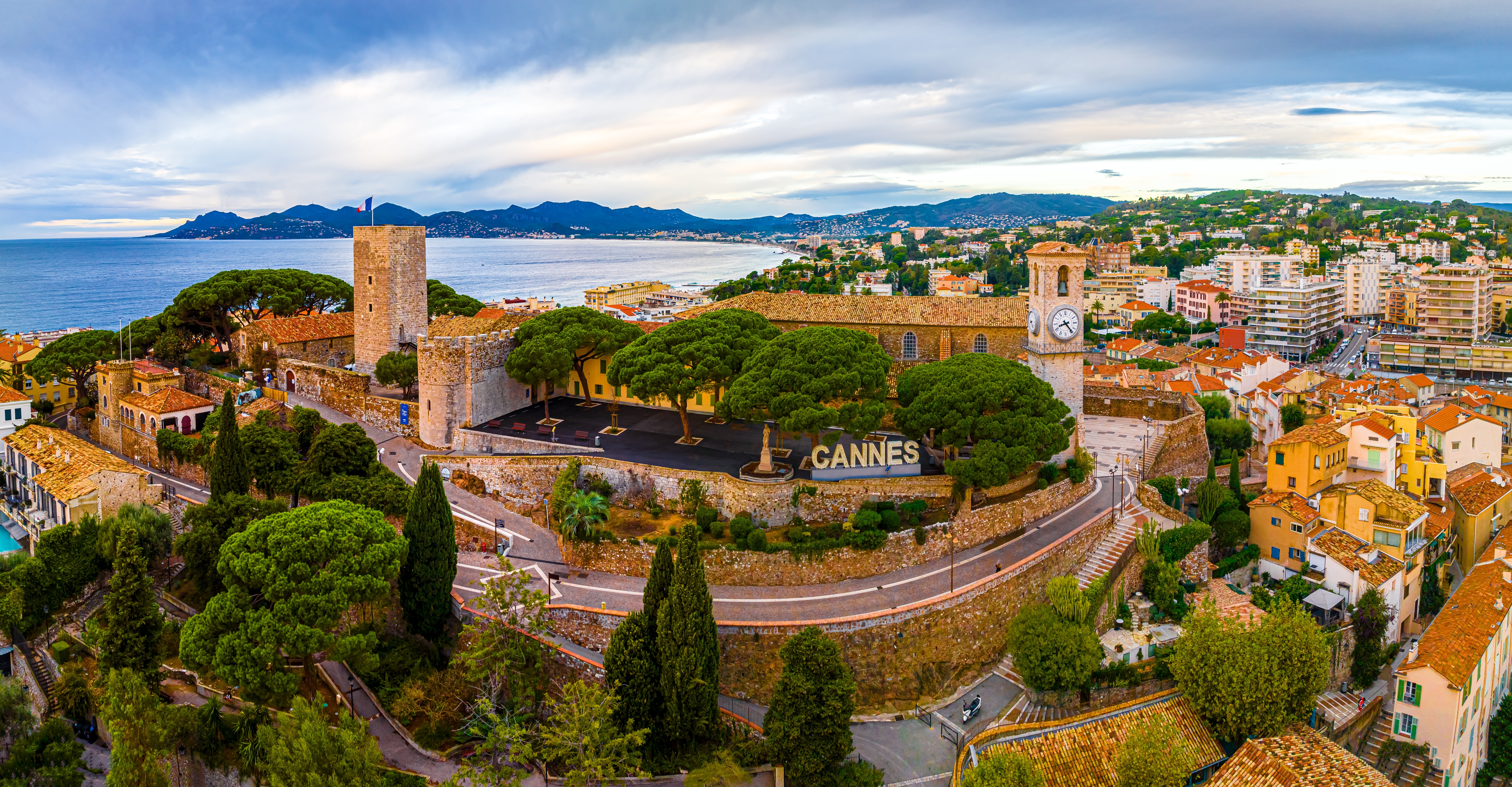 Fugleperspektiv over Cannes gamle bydel med historisk slot, klokketårn og det blå Middelhav på den franske riviera