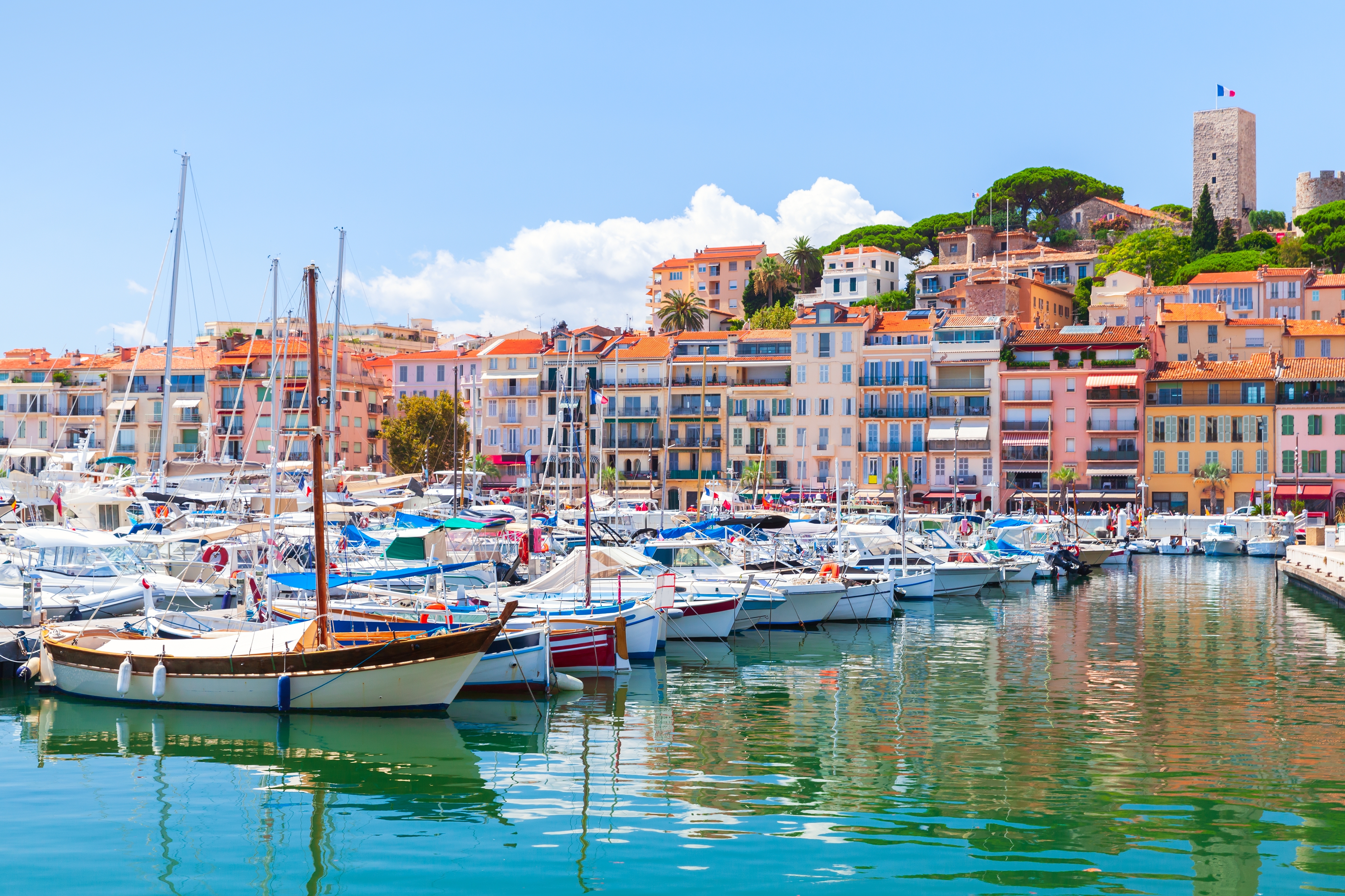 Panoramaudsigt over Cannes' havn med luksusbåde, farvestrålende bygninger og perfekt feriestemning under den sydfranske sol