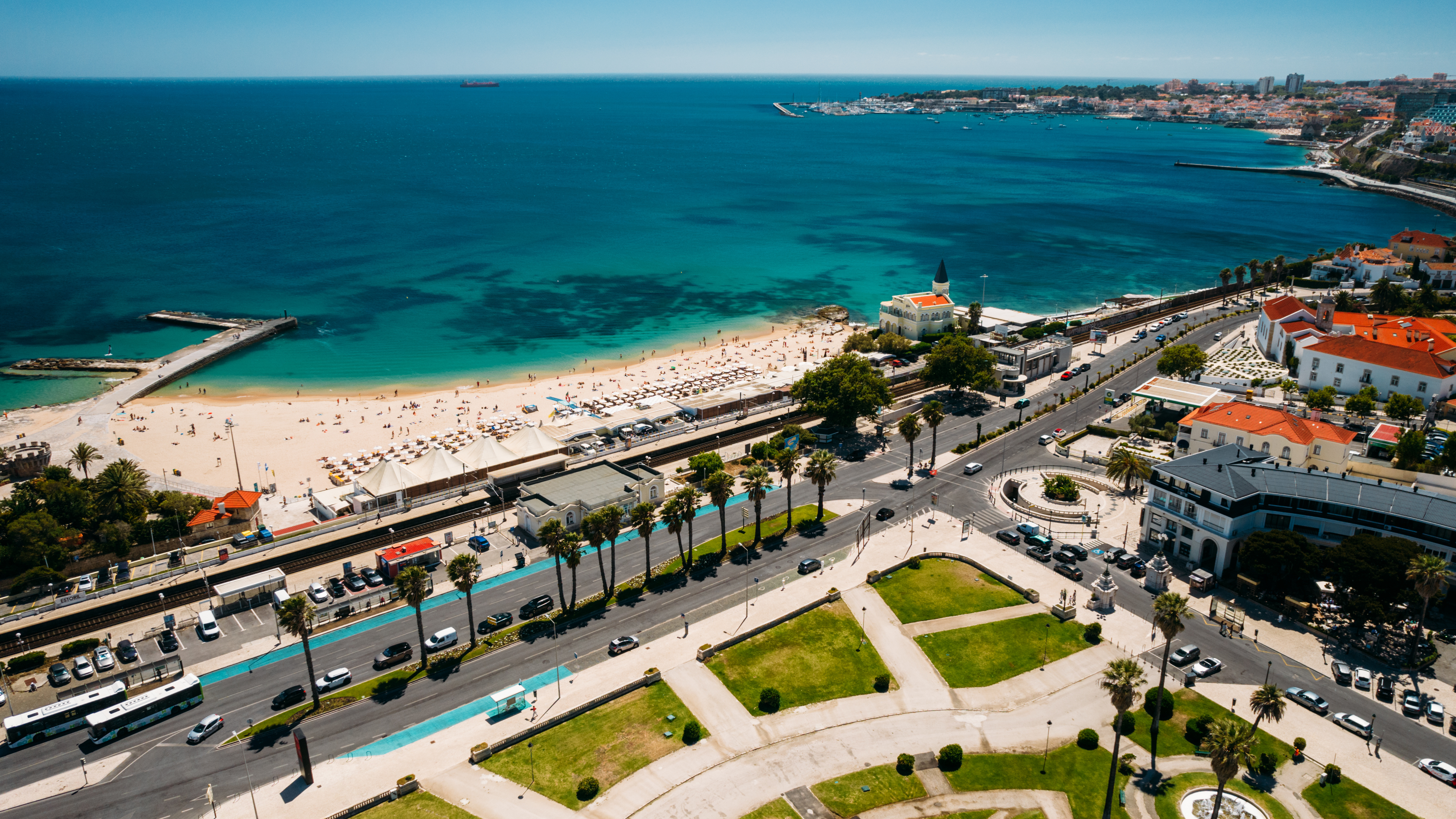 Panoramaudsigt fra luften over Cascais og Estoril-kysten med den indbydende Tamariz Strand, turkist hav og palmeboulevard i Portugal