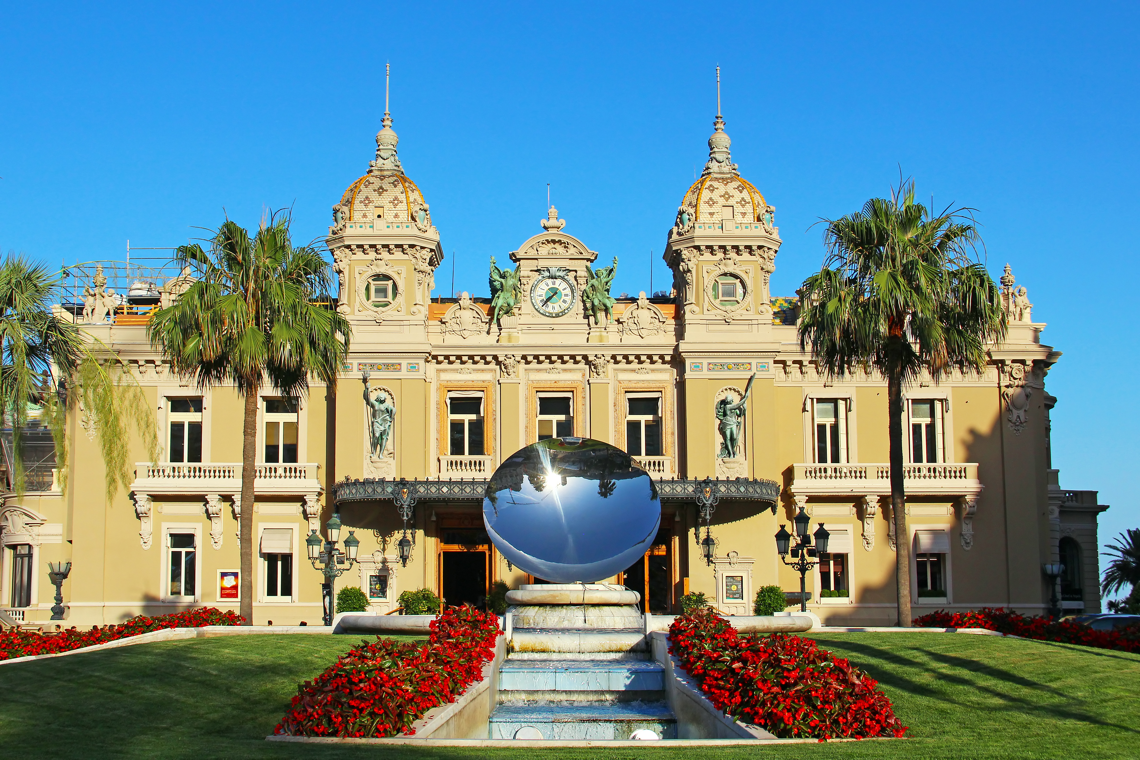 Historisk Casino de Monte-Carlo i Monaco med imponerende Belle Époque-arkitektur, palmer og en dekorativ spejlkugle ved indgangen