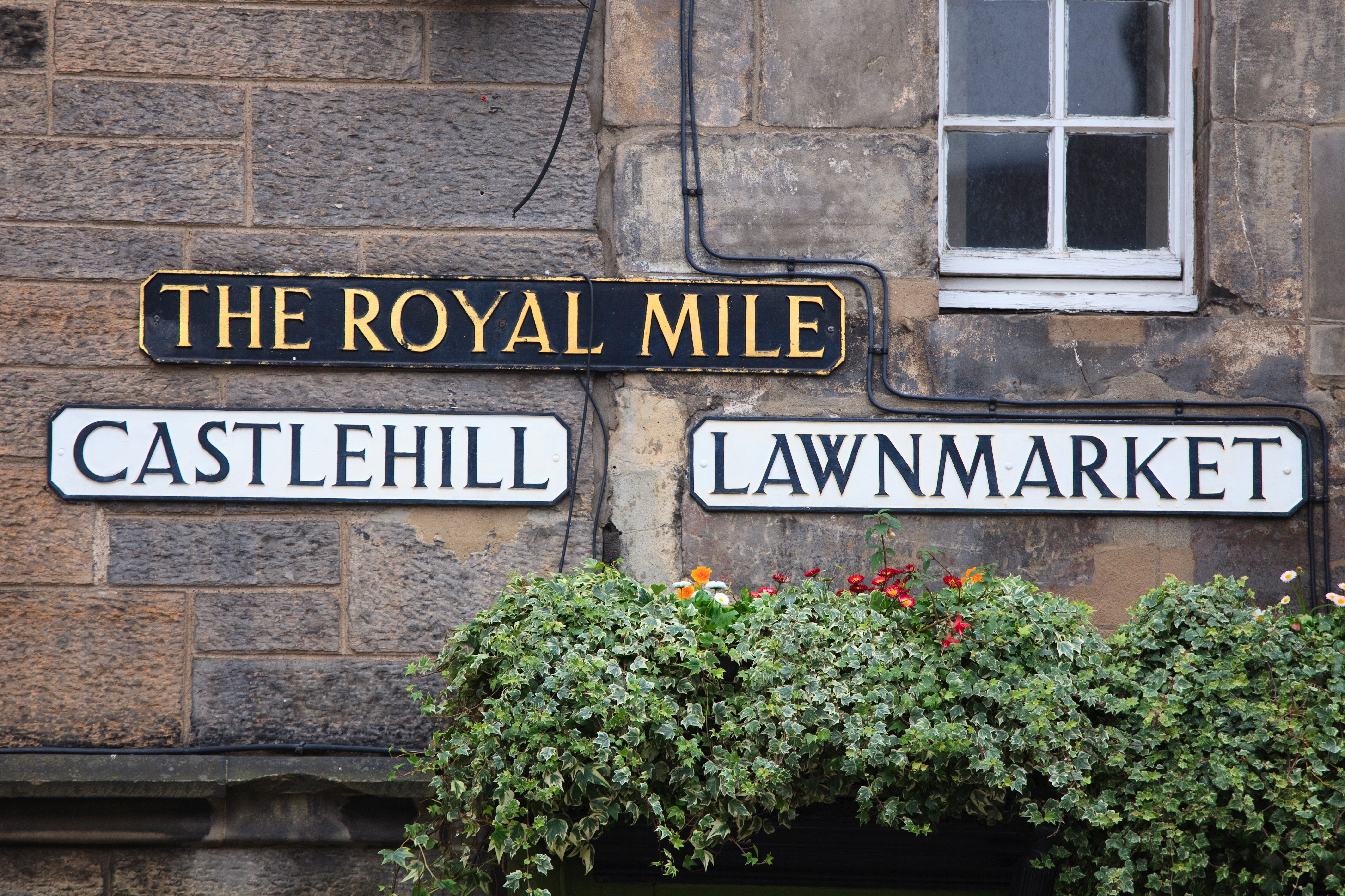 Gadeskiltene for The Royal Mile med Castlehill og Lawnmarket i Edinburgh, Skotland, pyntet med grønne planter og farverige blomster