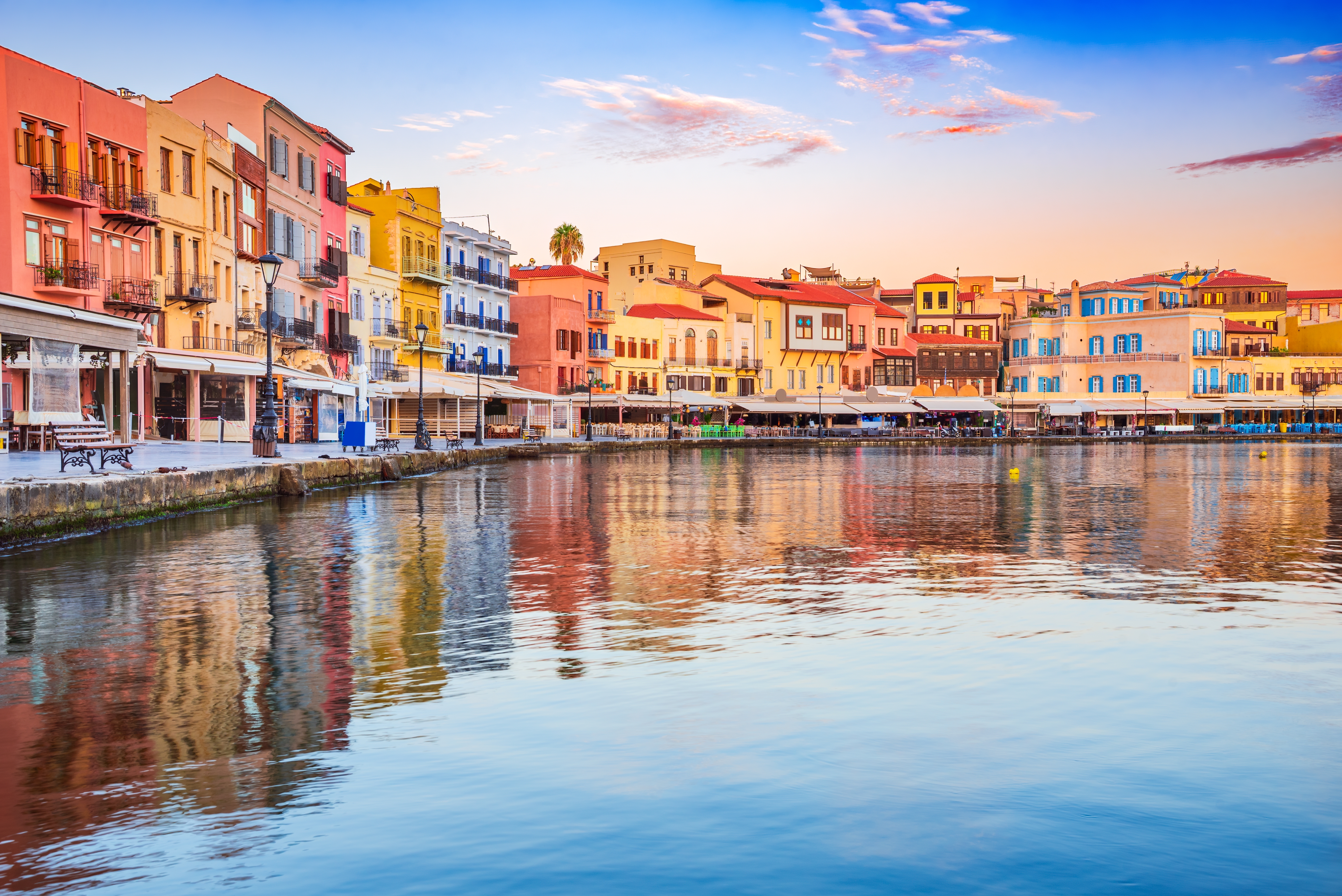 Idyllisk udsigt over den venetianske havn i Chania med farverige facade og refleksioner i det stille vand