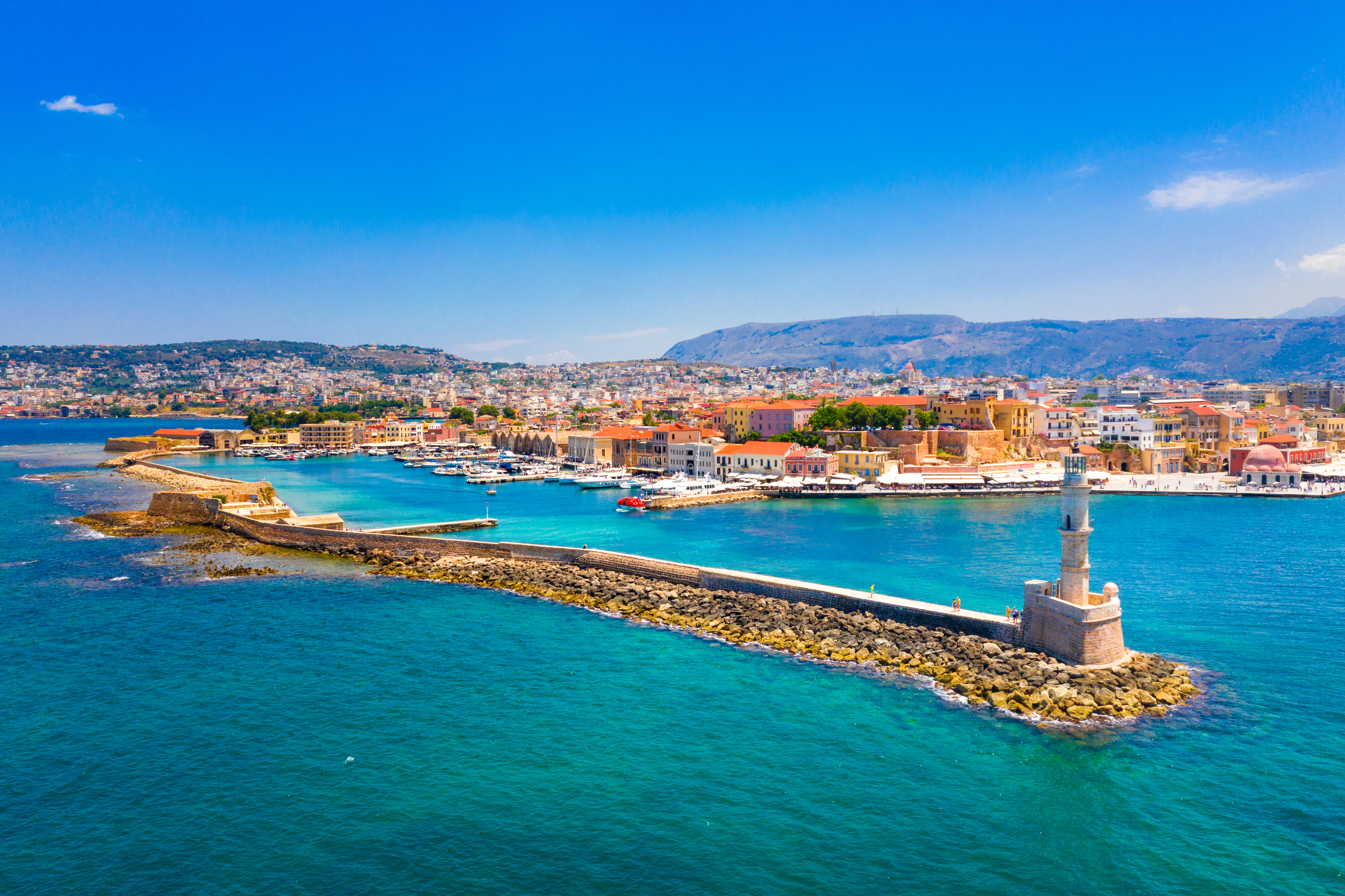 Smuk udsigt over Chania havn med det historiske fyrtårn og venetianske bygninger på Kreta omgivet af turkisfarvet vand