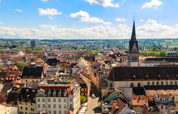 Charmerende europæisk by med gotisk kirke og røde tage i solskin med hvide skyer