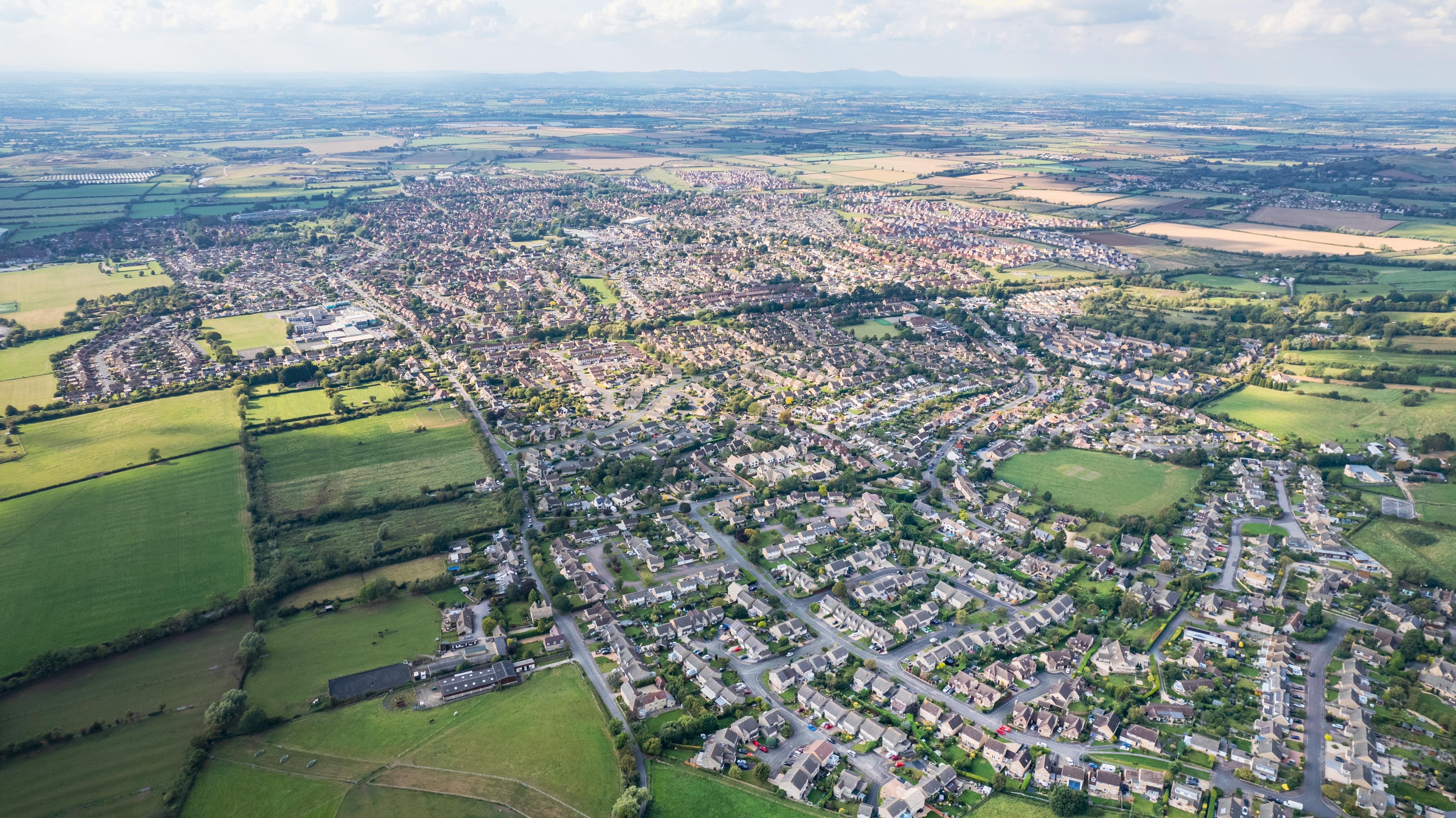 Flot dronefoto over Cheltenham by med omkringliggende landbrugsland i Gloucestershire