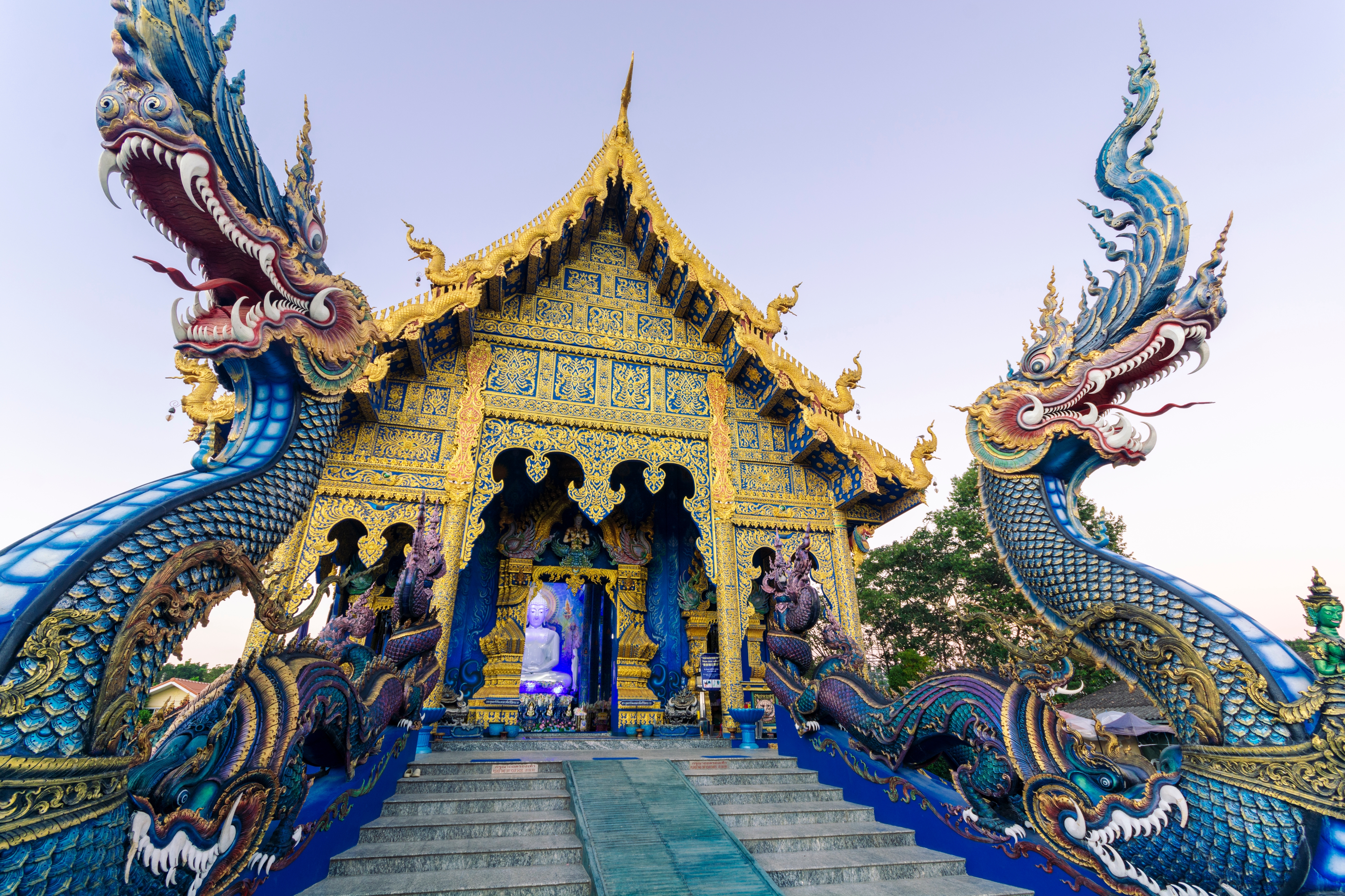 Majestætisk udsigt over det blå tempel Wat Rong Suea Ten i Chiang Rai, Thailand, med traditionelle buddhistiske naga-dragefigurer og gulddekoreret tempelindgang