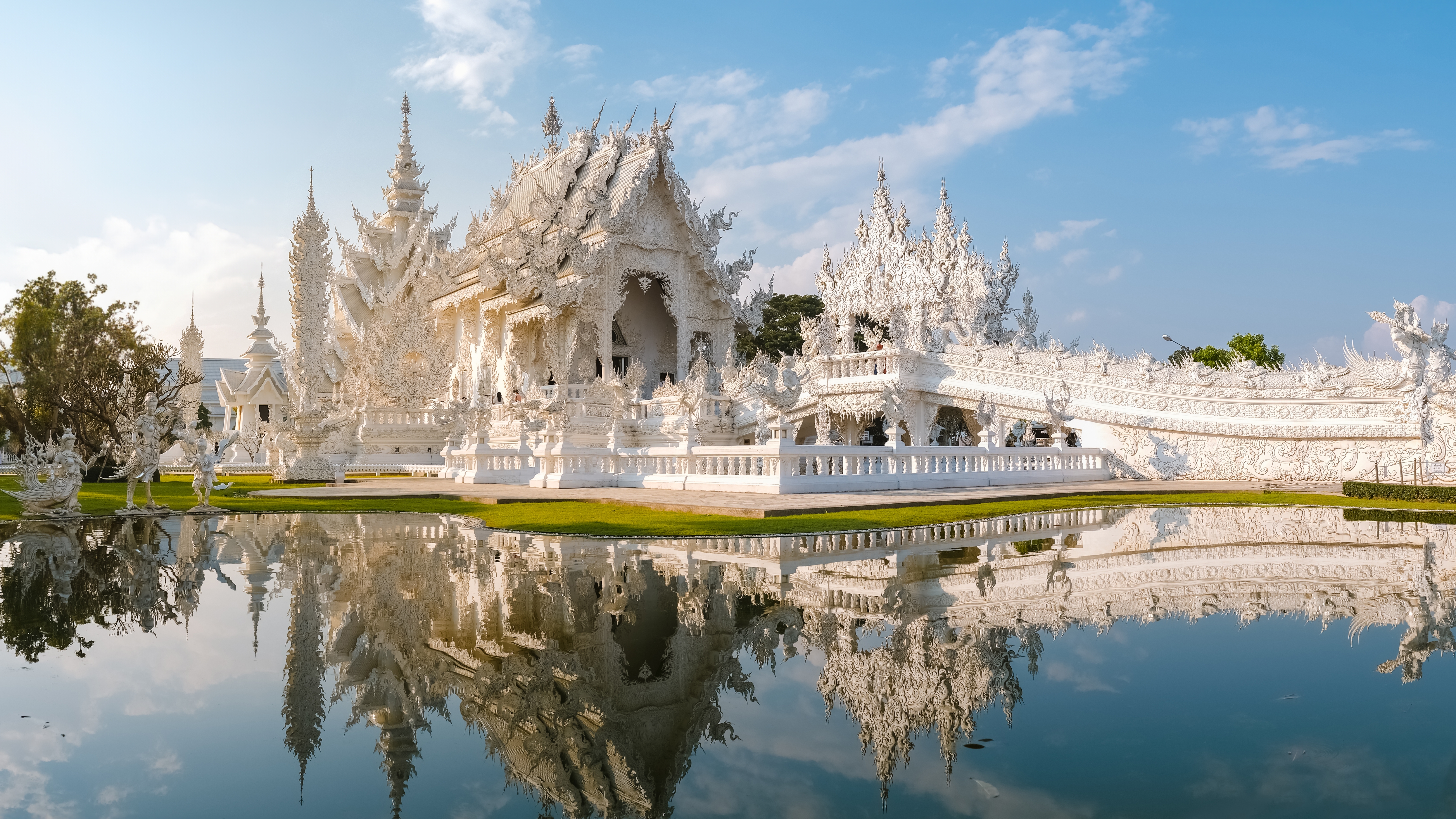 Det smukke hvide tempel Wat Rong Khun i Chiang Rai, Thailand, omgivet af vand og blå himmel