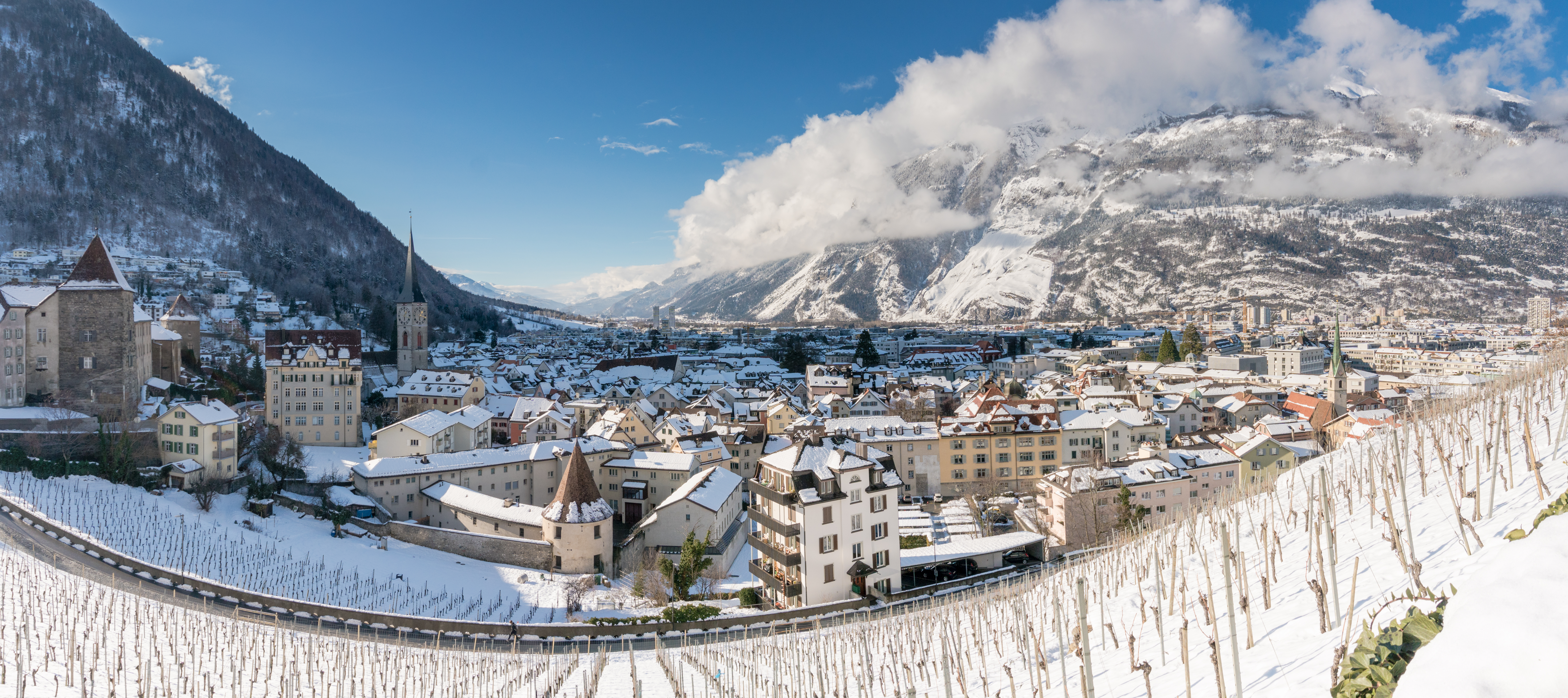 Vinterudsigt over Chur i det schweiziske kanton Graubünden med historiske bygninger, kirketårne og snedækkede bjerge