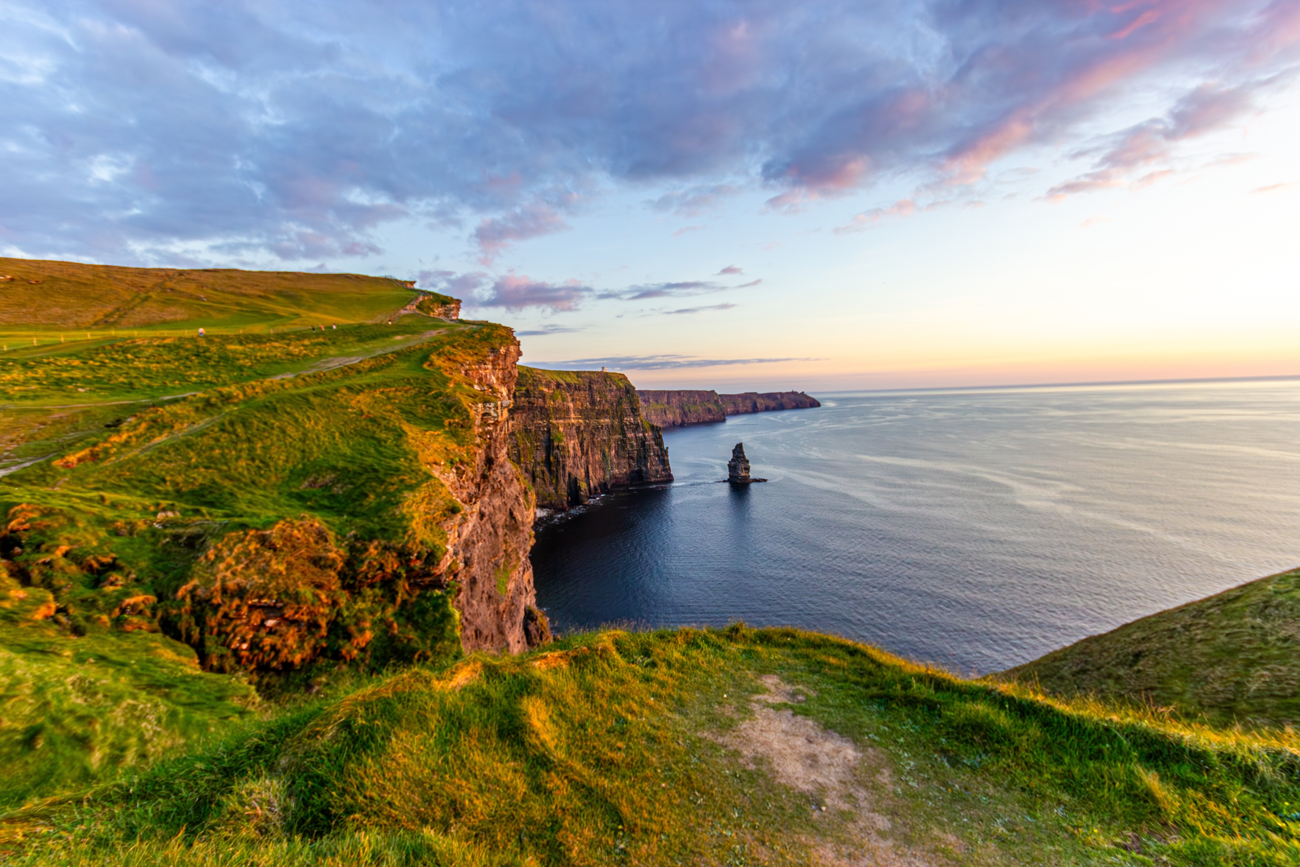 De imponerende Cliffs of Moher i County Clare, Irland, badet i varmt solnedgangslys med udsigt over det åbne Atlanterhav