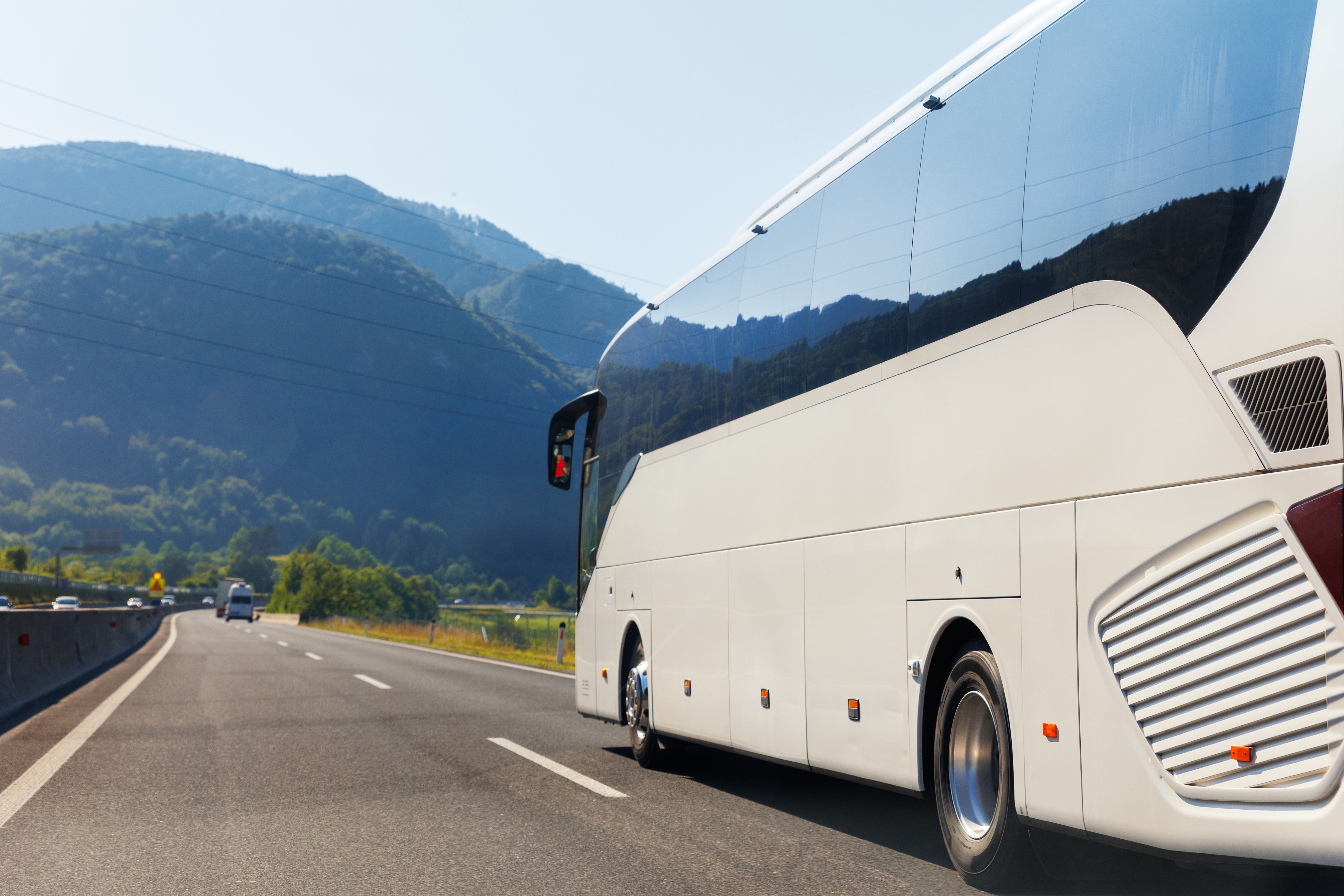Moderne hvid coach bus på vej gennem alpine bjerge i Europa på en smuk solrig sommerdag