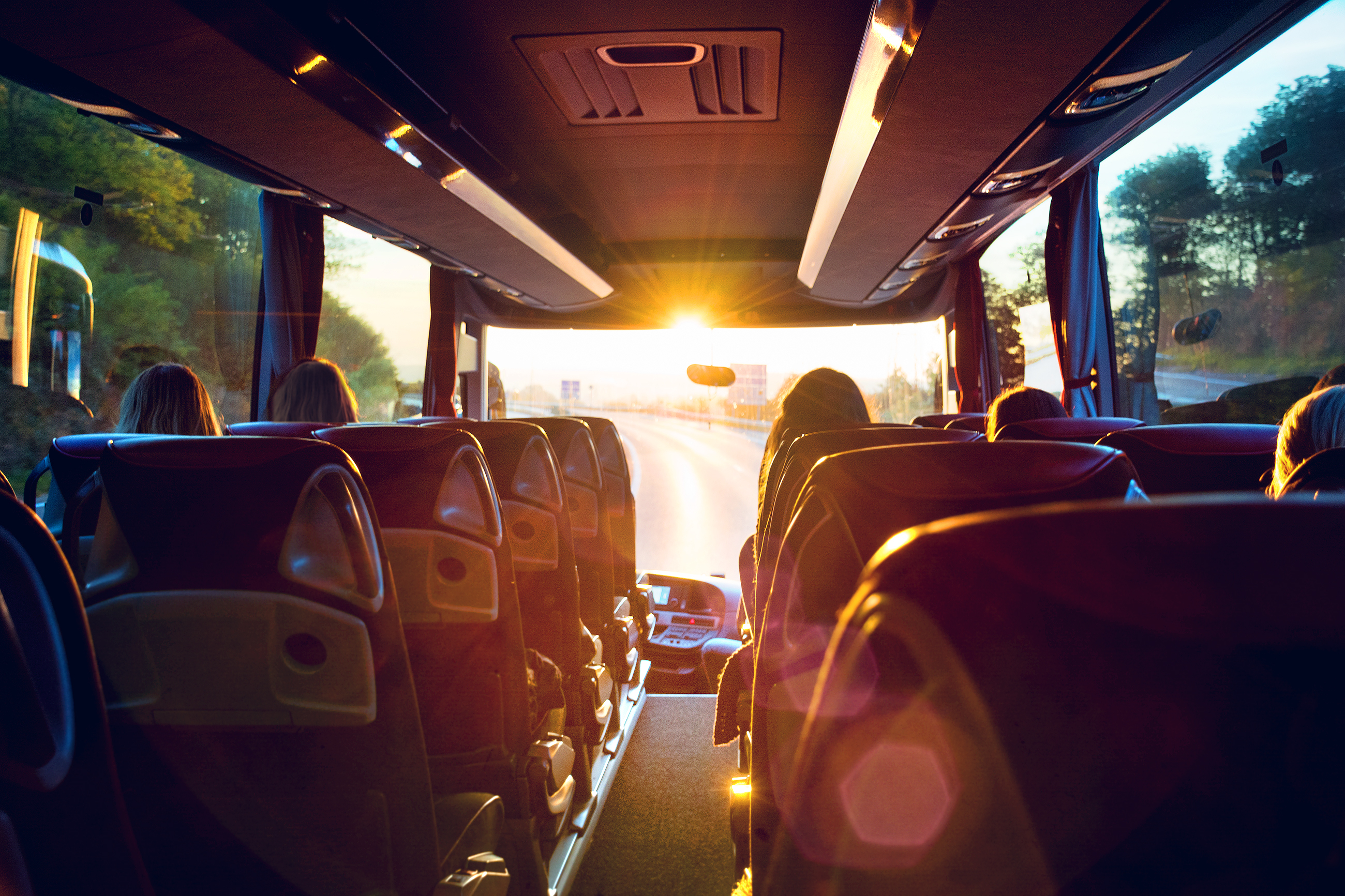 Coach bus med passagerer på tur i gyldent aftenlys