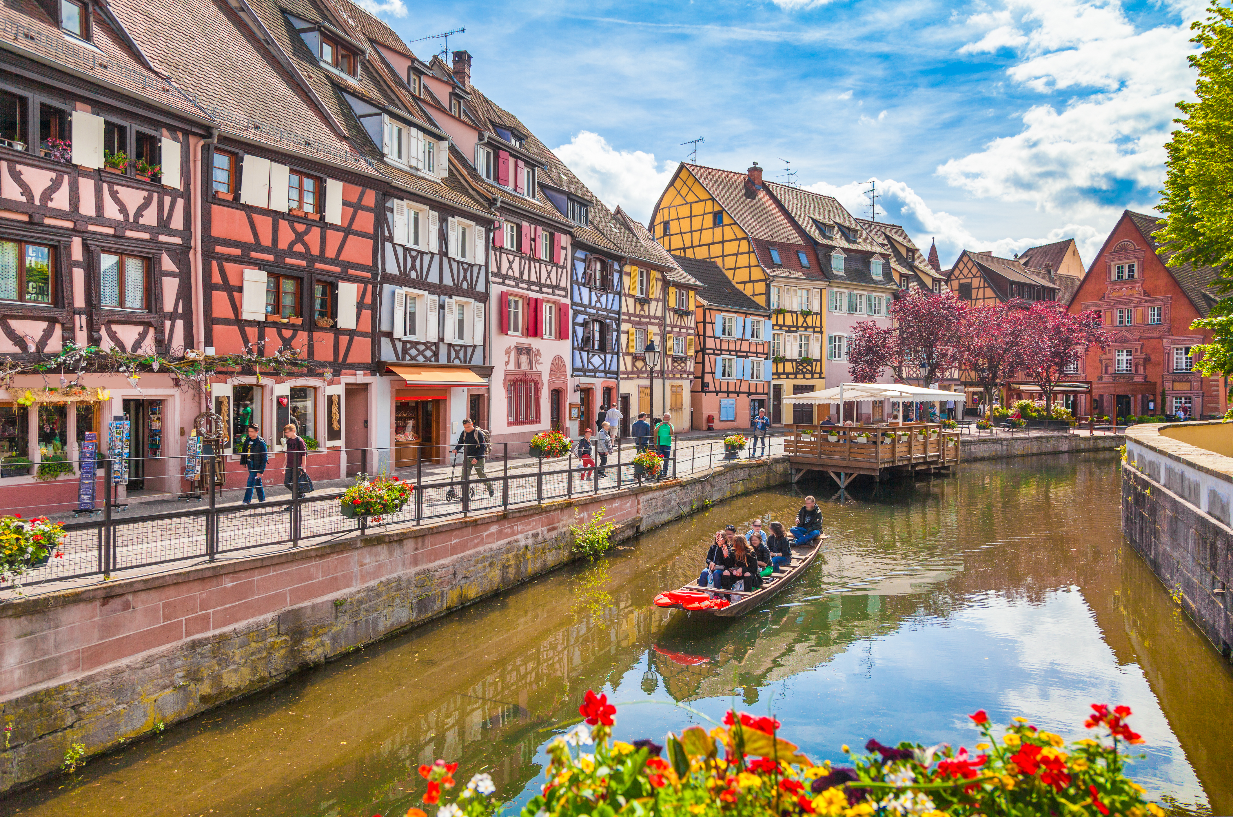 Smuk udsigt over kanalen i Colmar med farverige bindingsværkshuse og turister på båd i det historiske Lille Venedig, Alsace