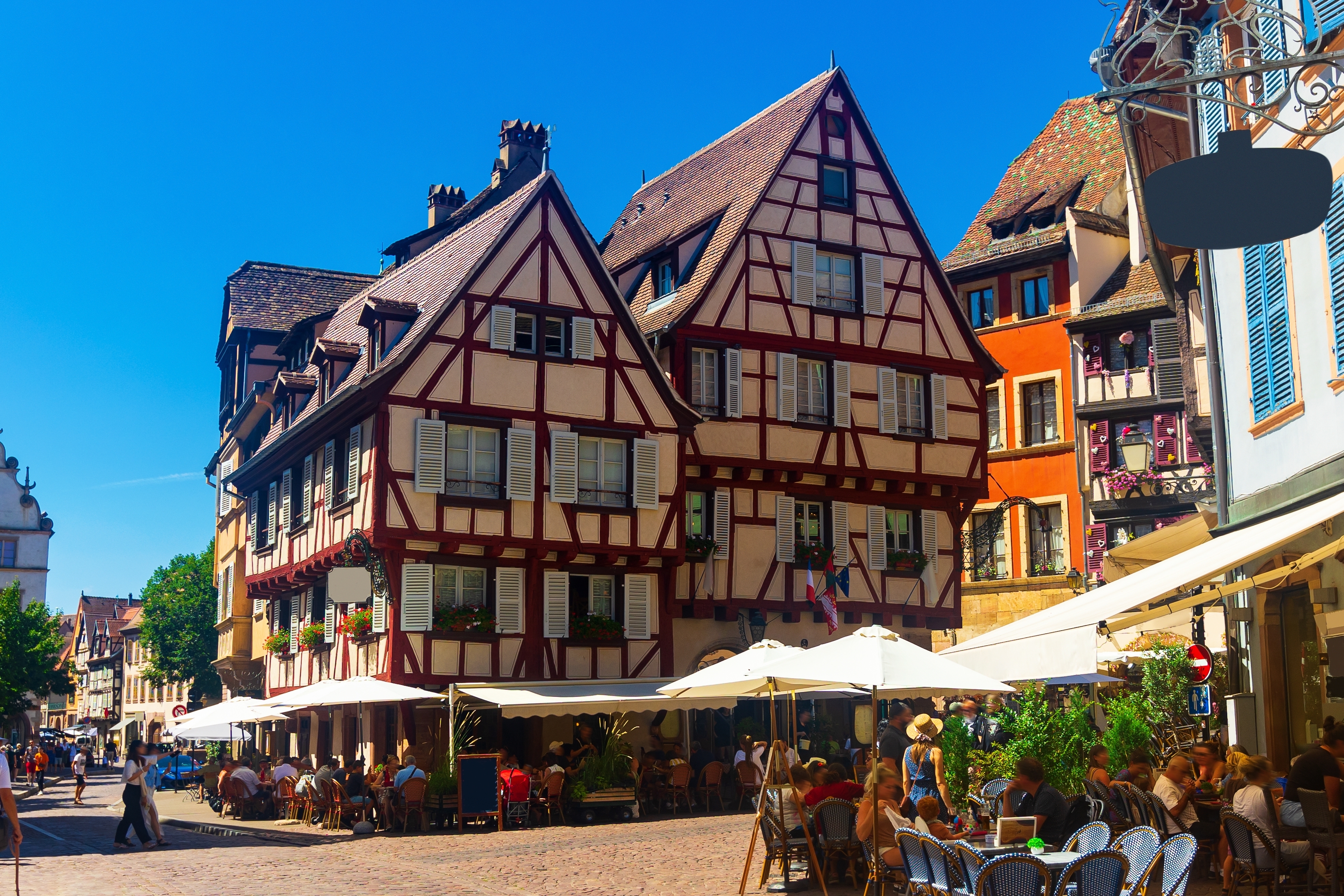 Hyggelige udendørs caféer foran smukke historiske bindingsværkshuse i Colmar, Frankrig