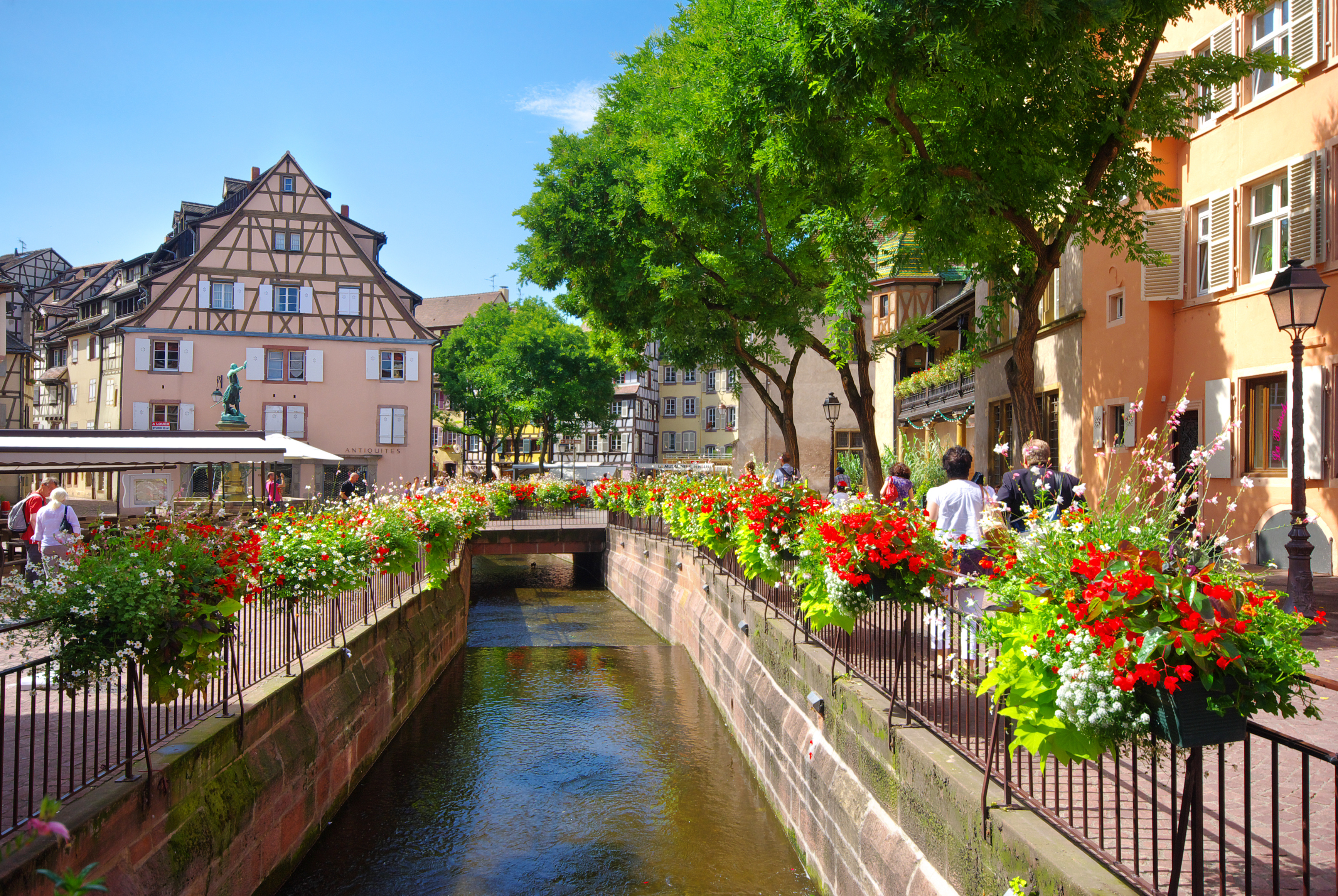 Hyggelig kanalscene i Colmar, Alsace med farverige blomster og traditionelle franske bindingsværkshuse langs vandvejen