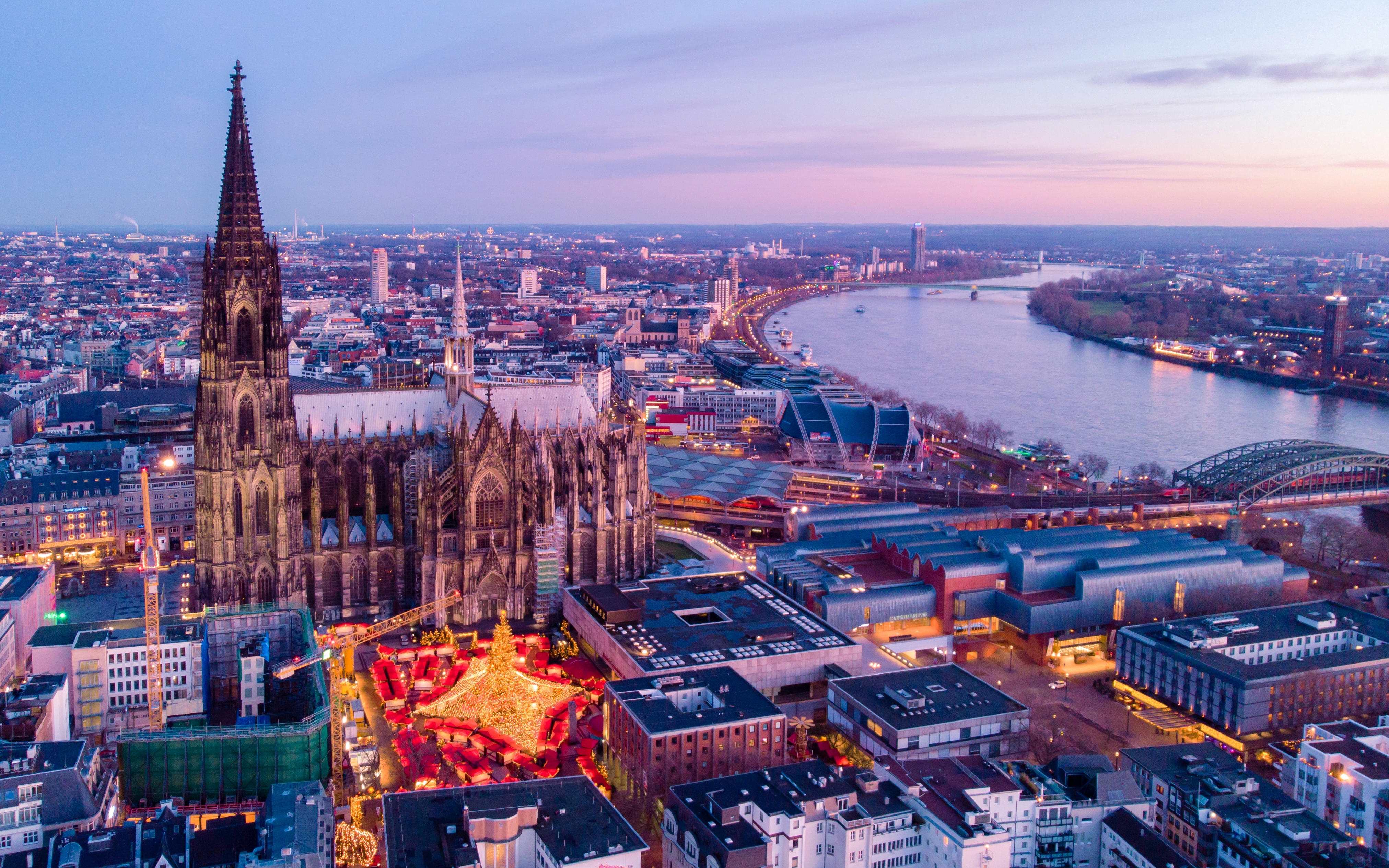 Kölns gotiske domkirke og traditionelle julemarked fotograferet fra luften ved solnedgang