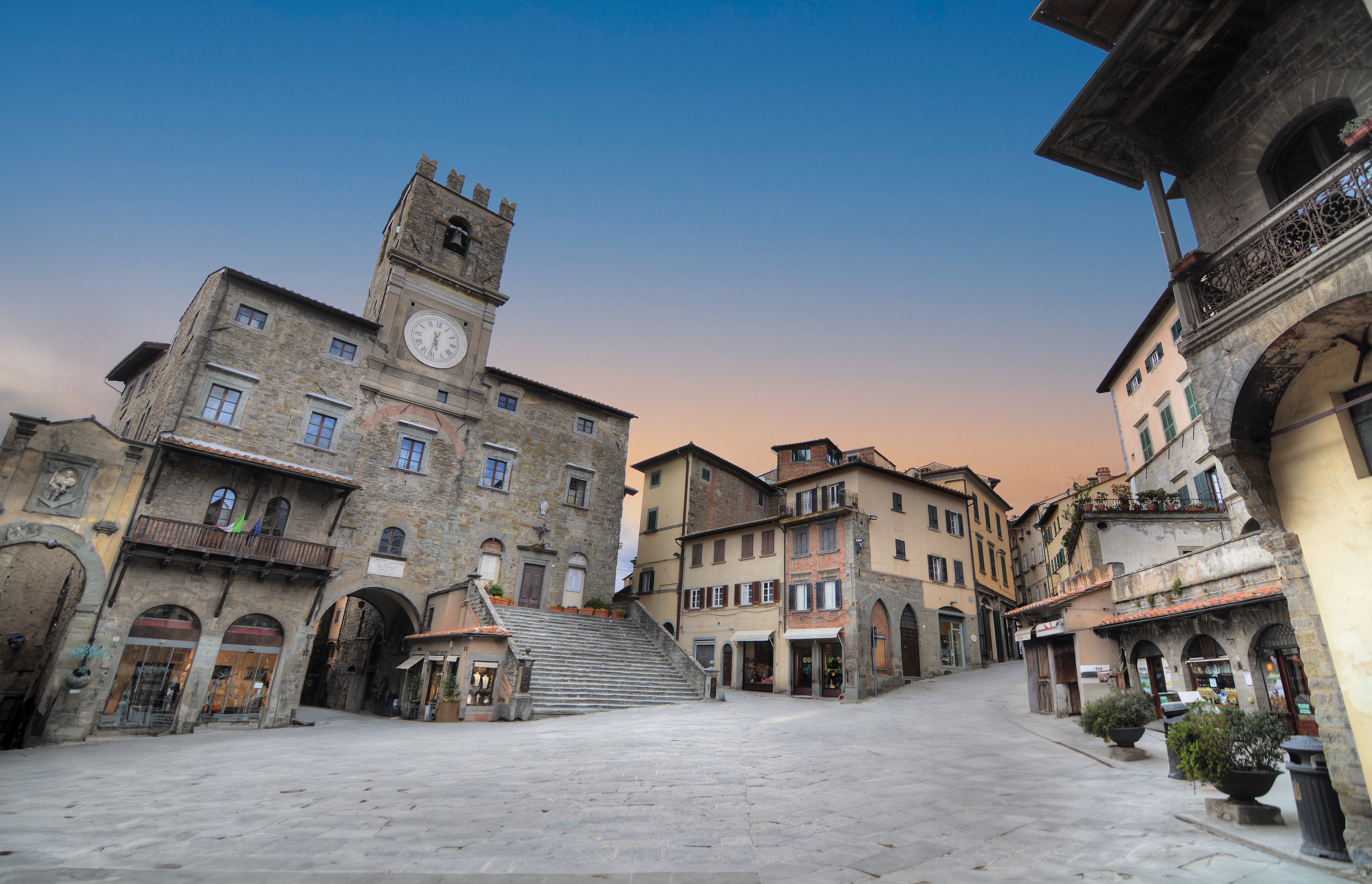 Charmerende middelalderplads i Cortona med italiensk arkitektur og solnedgang