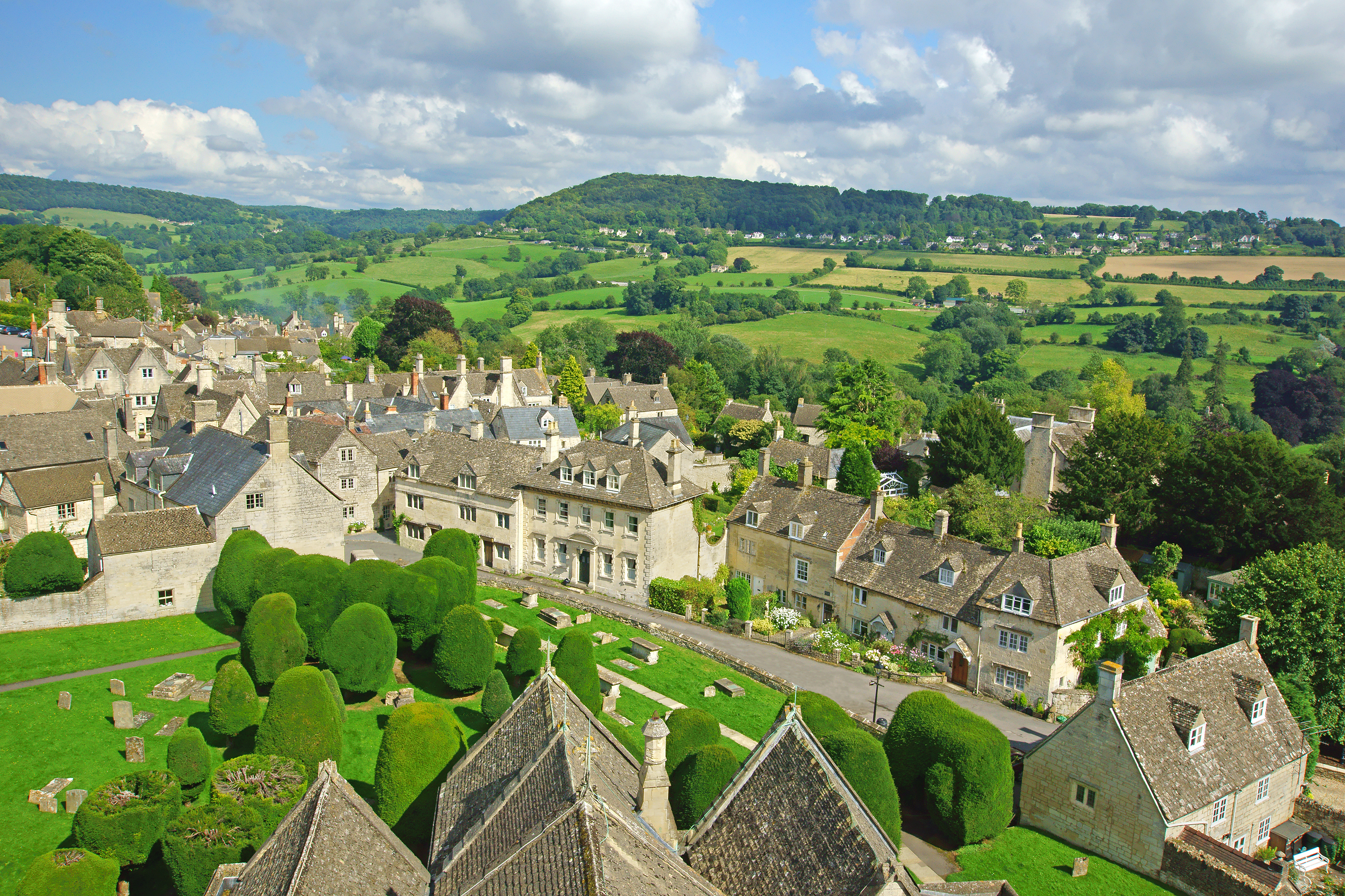 Dronefoto af charmerende Cotswolds landsby med gamle stenhuse og kirkegård