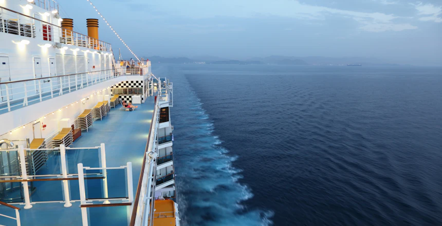 Aftenudsigt fra cruise skibsdæk med dyb blå ocean og hvide skumstriber