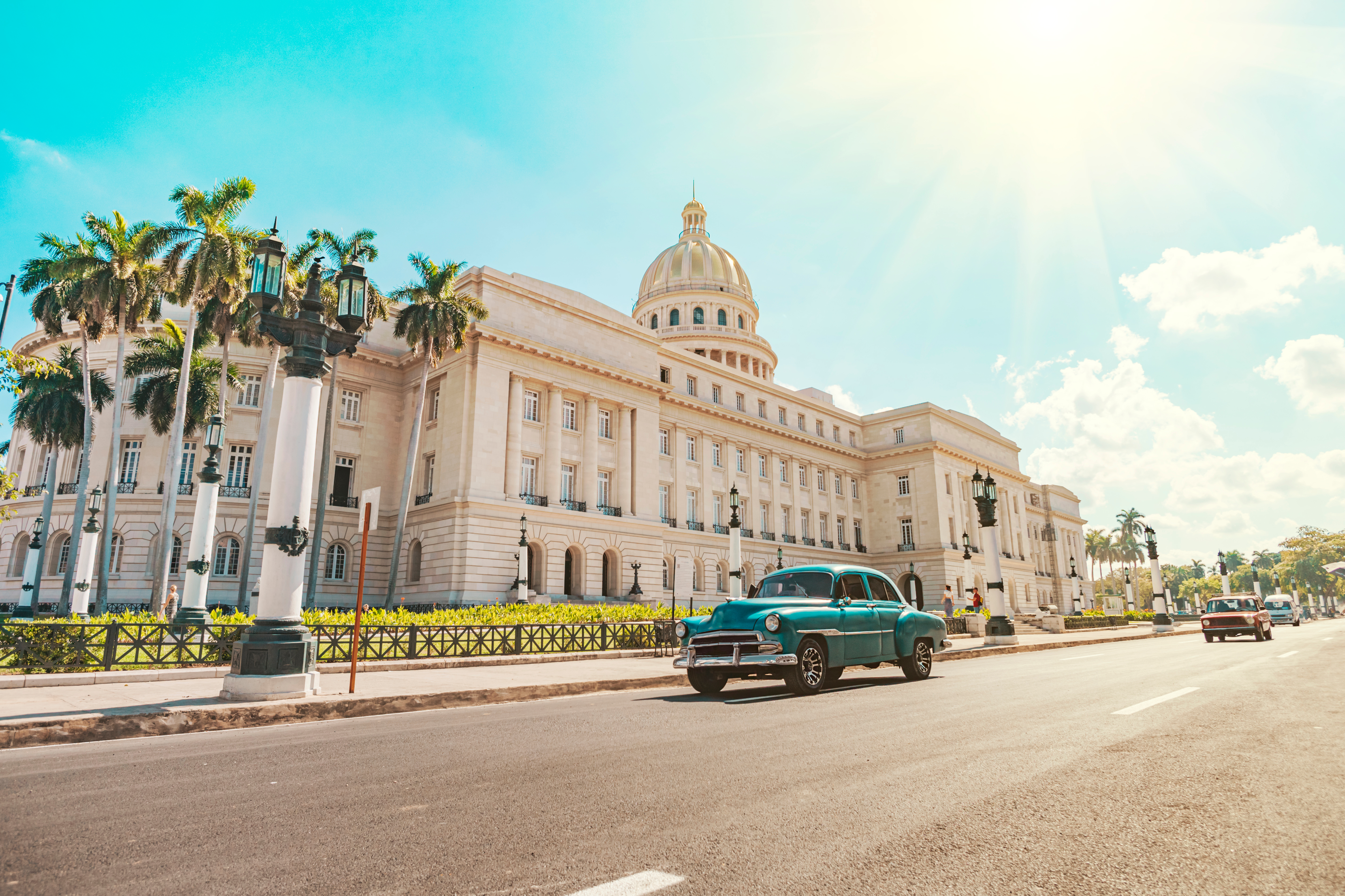 Autentisk cubansk street scene med klassisk bil og det majestætiske Capitol i Havana omgivet af tropiske palmer