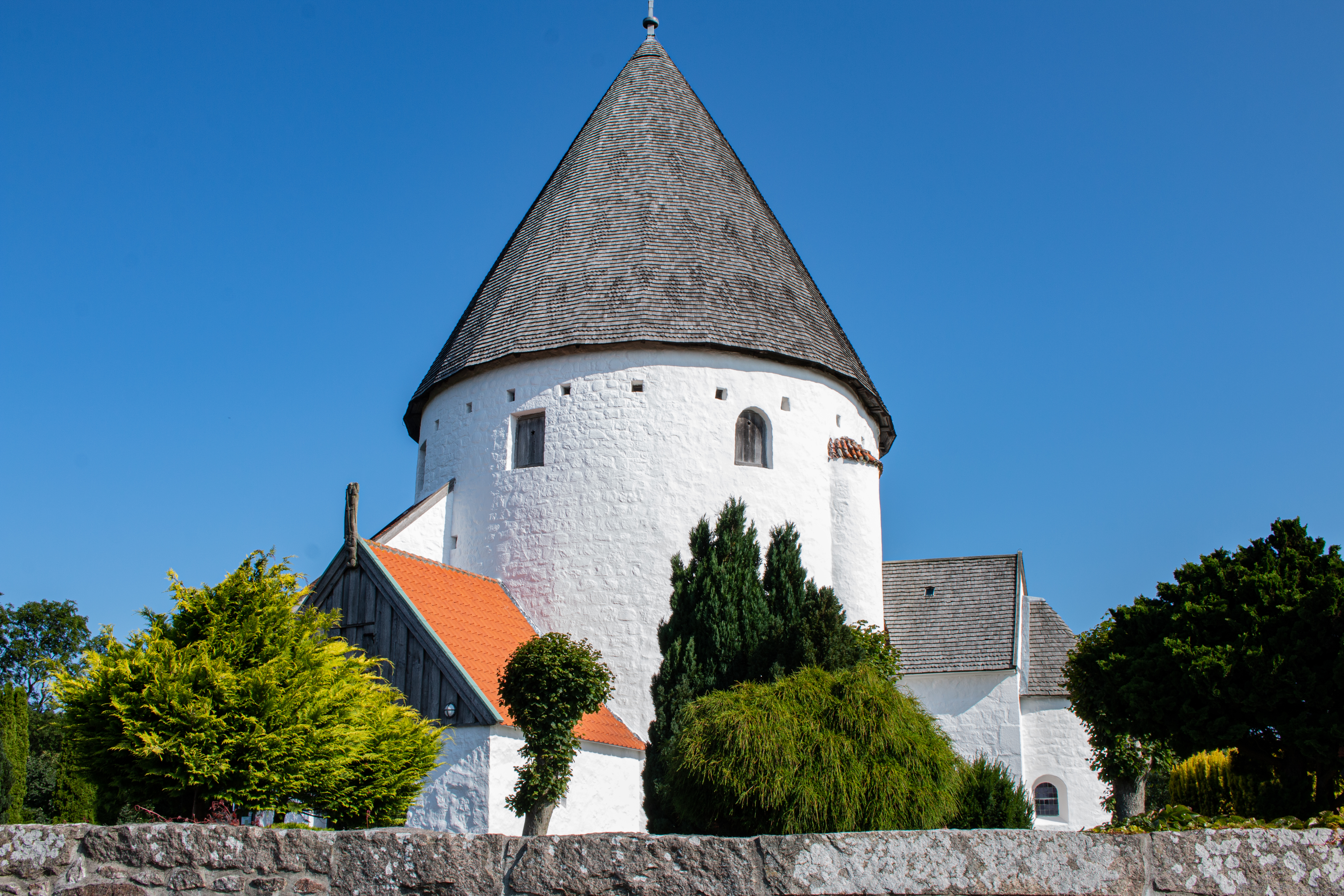Dansk historisk rundkirke med hvide kalkmure og skifertag