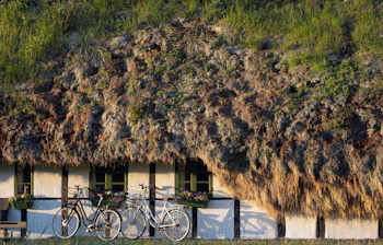 Autentisk bindingsværkshus med det berømte grønne tangtag på Læsø, en del af tangruten hvor besøgende kan opleve øens enestående bygningsarv med cyklen parkeret i forgrunden